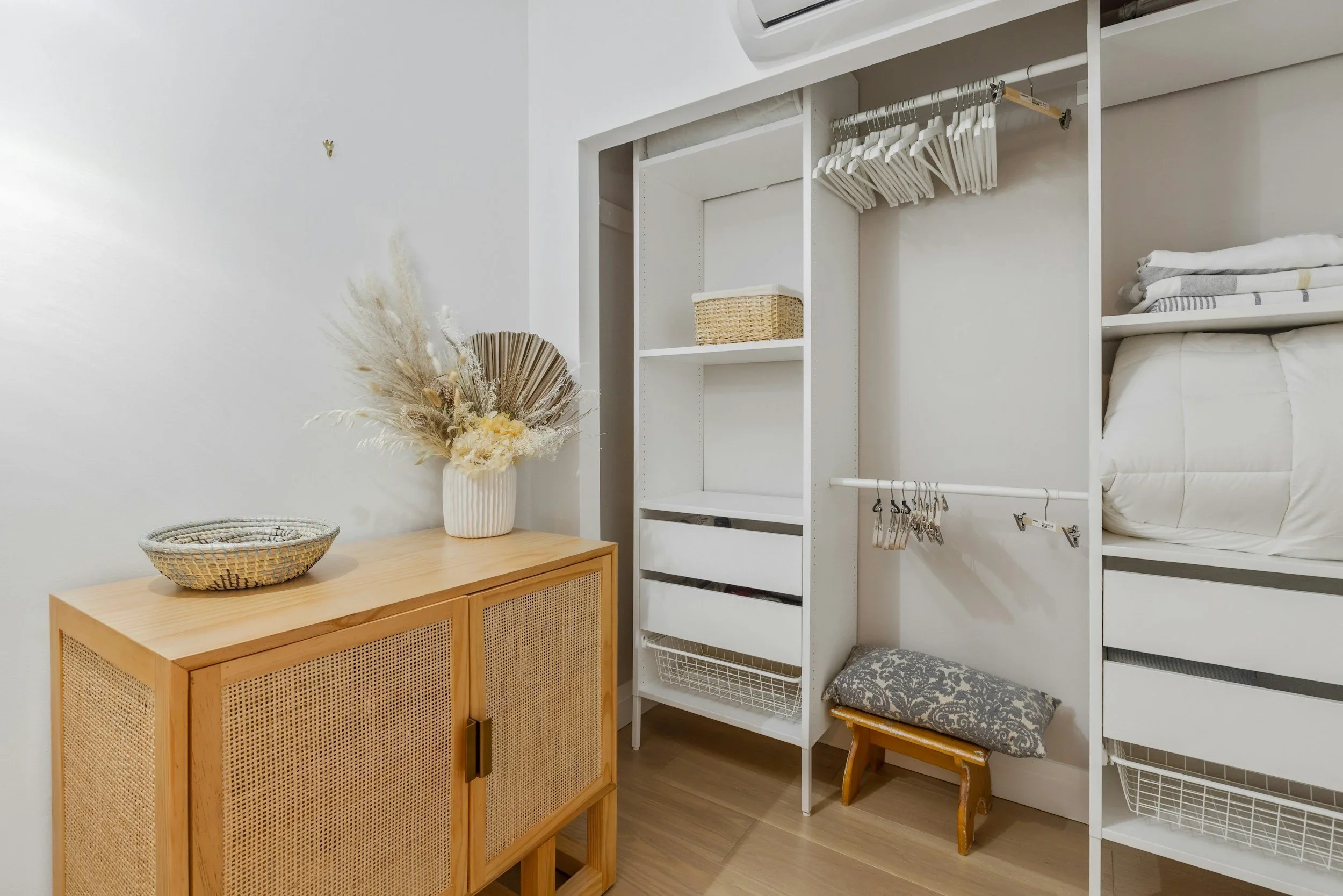 Minimalist white closet and light wood cane dresser organized by Greyspace Organizing in Los Angeles.