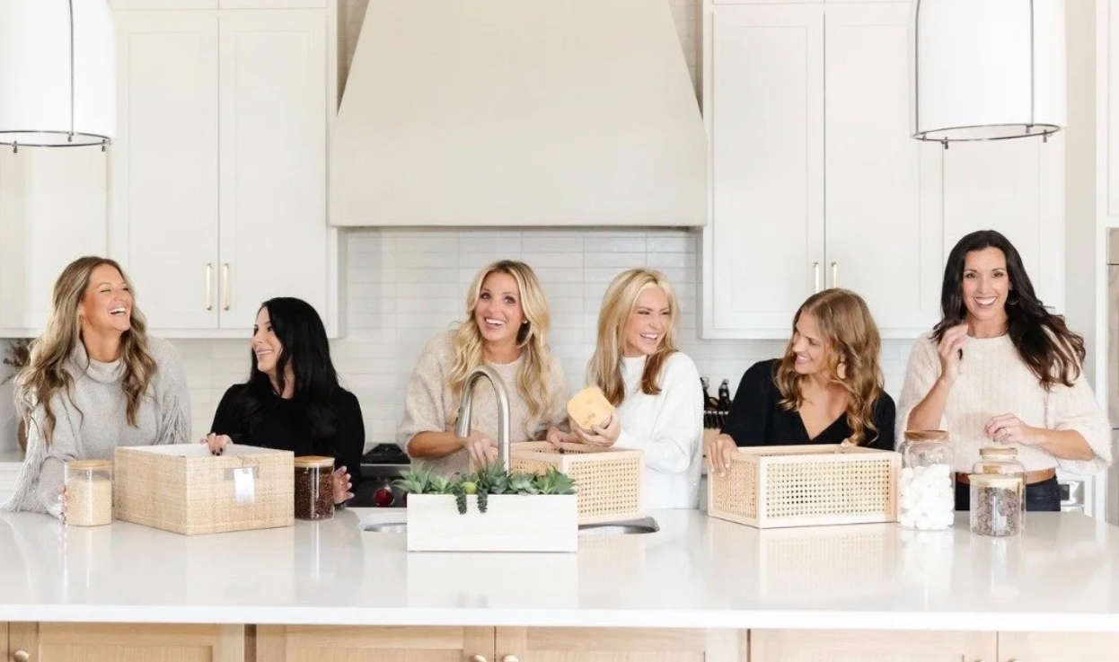 The professional home organizing team of Incredibly Organized, including owner Jamie Kisler, laughing in a modern Dallas kitchen.