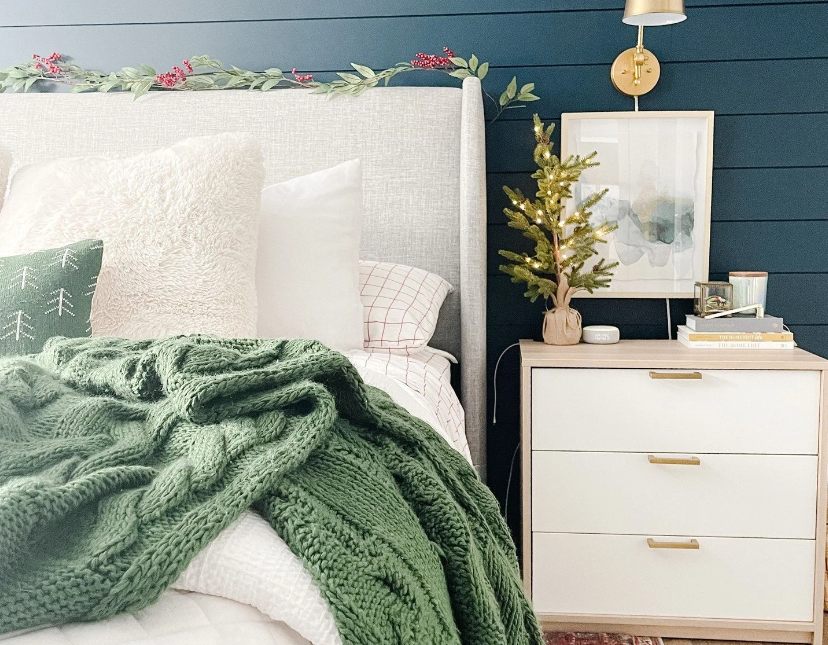 Professional bedroom styling by Reset Your Nest in Utah, featuring a navy shiplap accent wall, a green knit throw, and an organized nightstand with a mini pine tree.