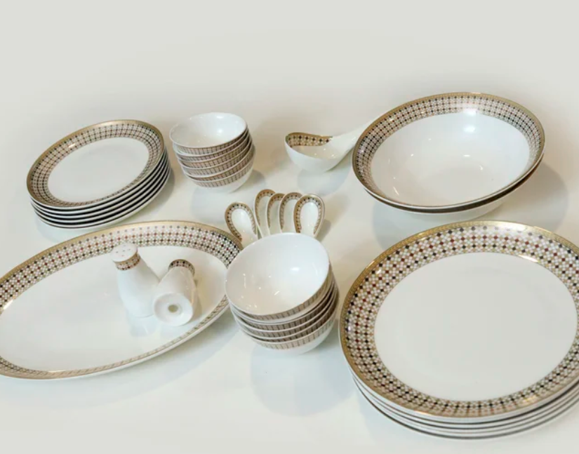 A white ceramic dinnerware set with gold patterned rims, including neatly stacked plates and bowls, organized by Joyful Order Organizing.