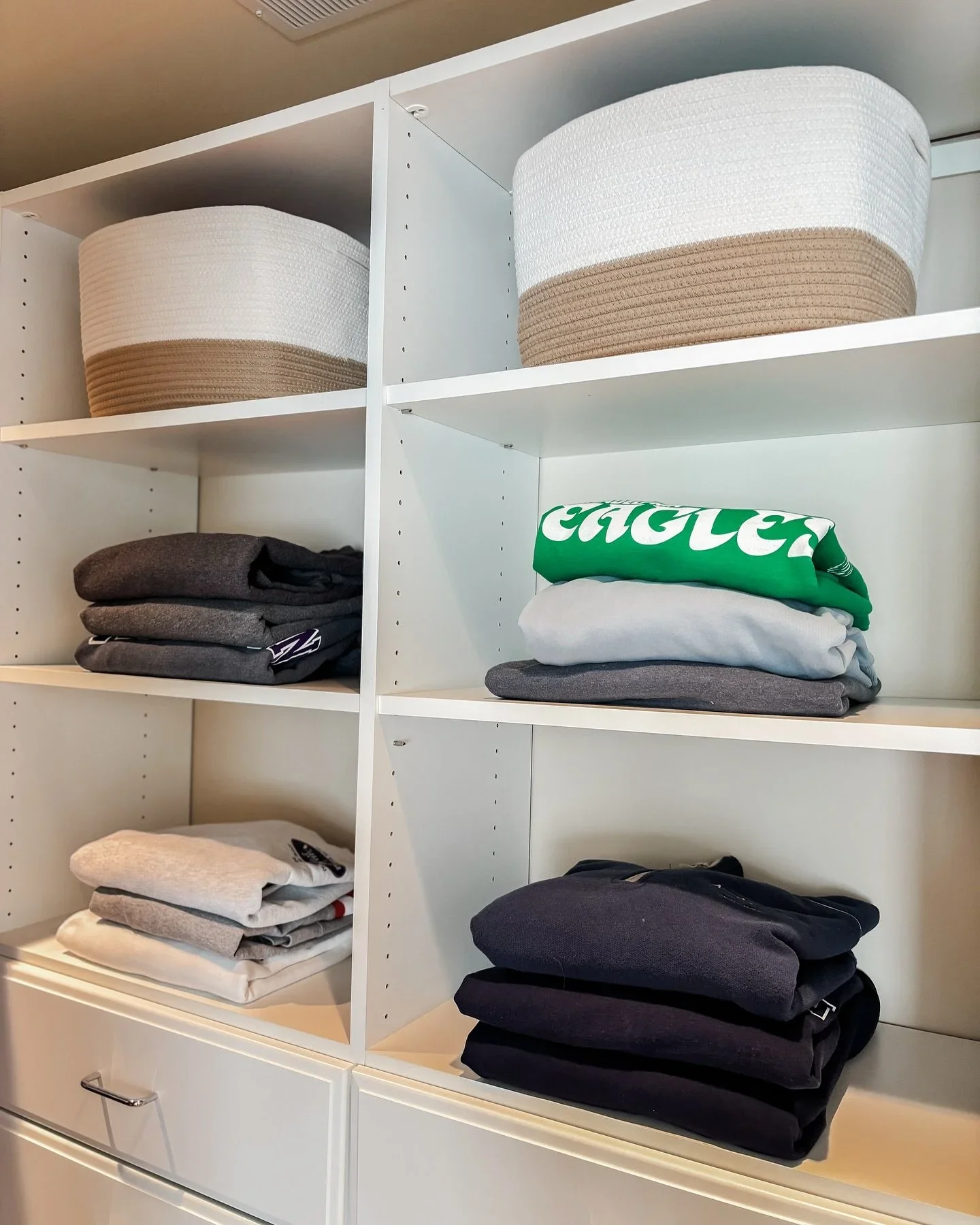 Professional closet organization in Manahawkin, NJ by Orderly at the Shore, featuring neatly folded sweaters and white woven rope baskets on shelving.