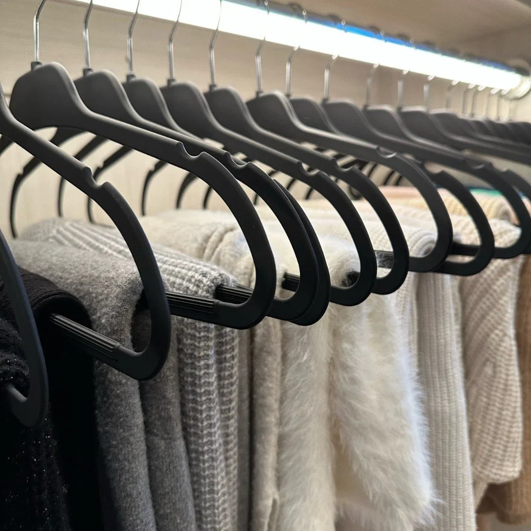 Organized by Keli & Co. closet organization in Denver featuring uniform black slim hangers and color-coordinated sweaters.