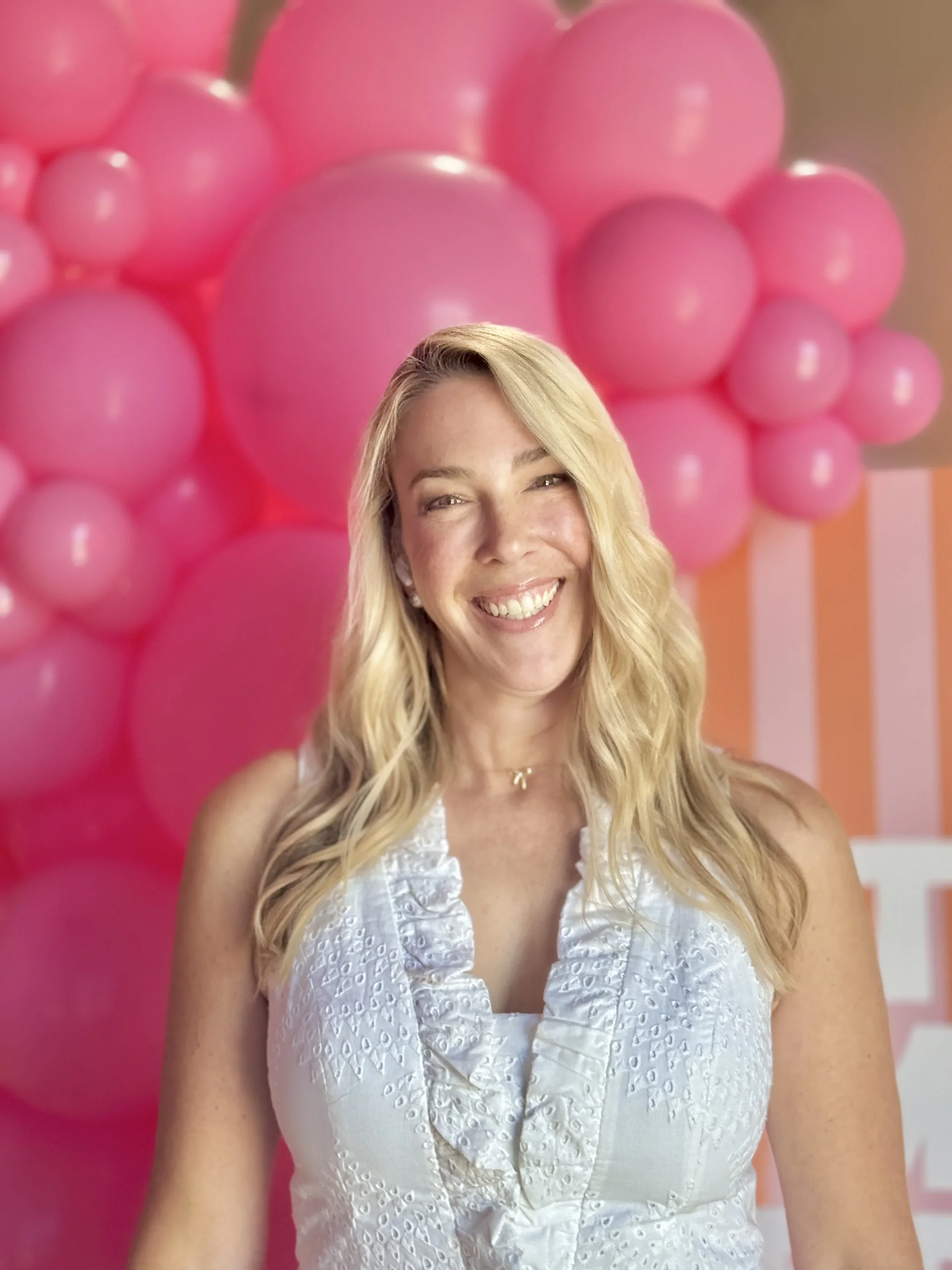 Professional organizer Stephanie from Happy Tree Organizing smiling in front of pink balloons.