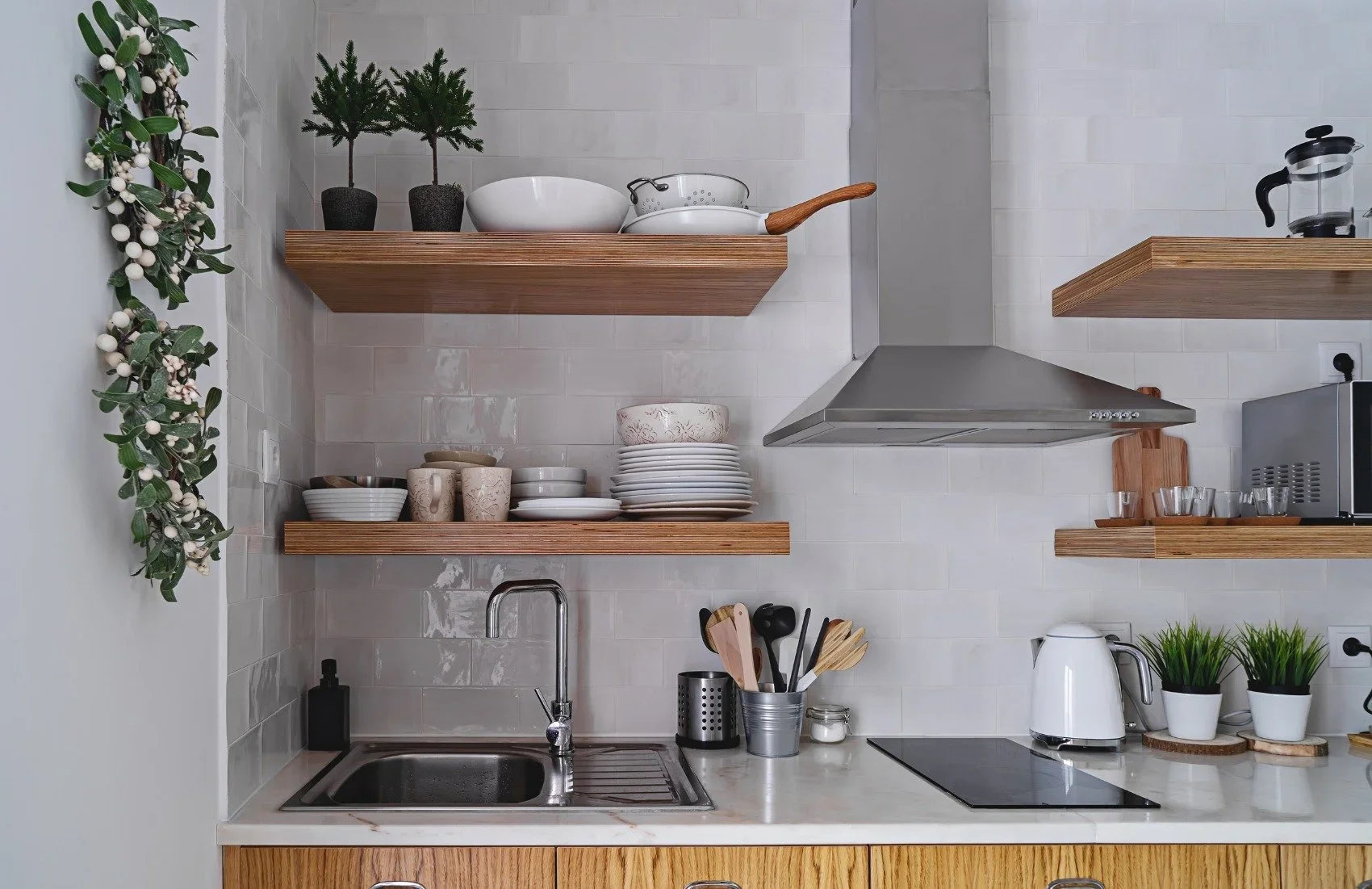 Organized kitchen featuring open wooden shelves, white dishes, and minimalist decor.