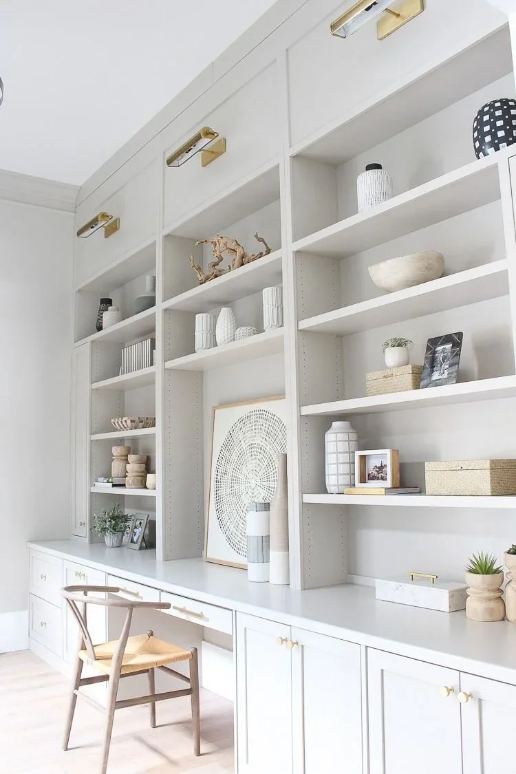 Professional home office organization by Divine Organization featuring light gray custom built-in shelves and a minimalist desk.
