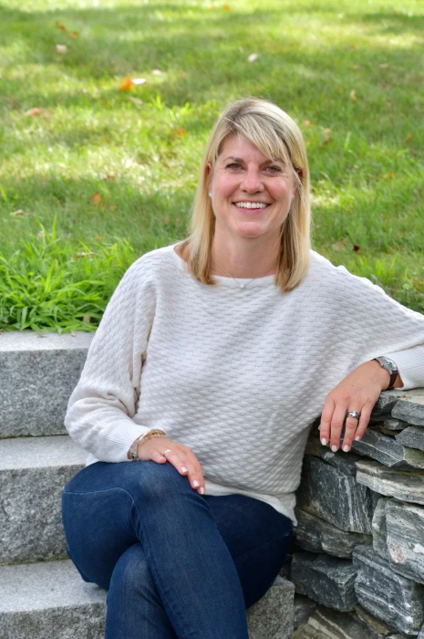 Judy Anderson, founder of All in Place Organizing in Greater Boston, sitting outdoors for a professional portrait in a white sweater.