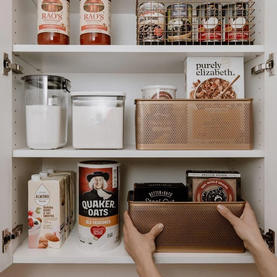 Professional pantry organization by Organized by Keli & Co. in Denver, featuring labeled glass jars and bronze perforated baskets on white shelving.