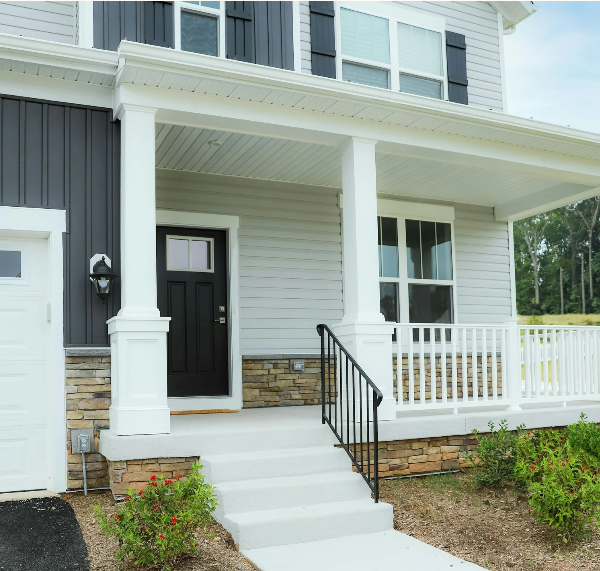A modern home entrance in Denver with a black front door, white columns, and stone siding by Organized by Keli & Co.