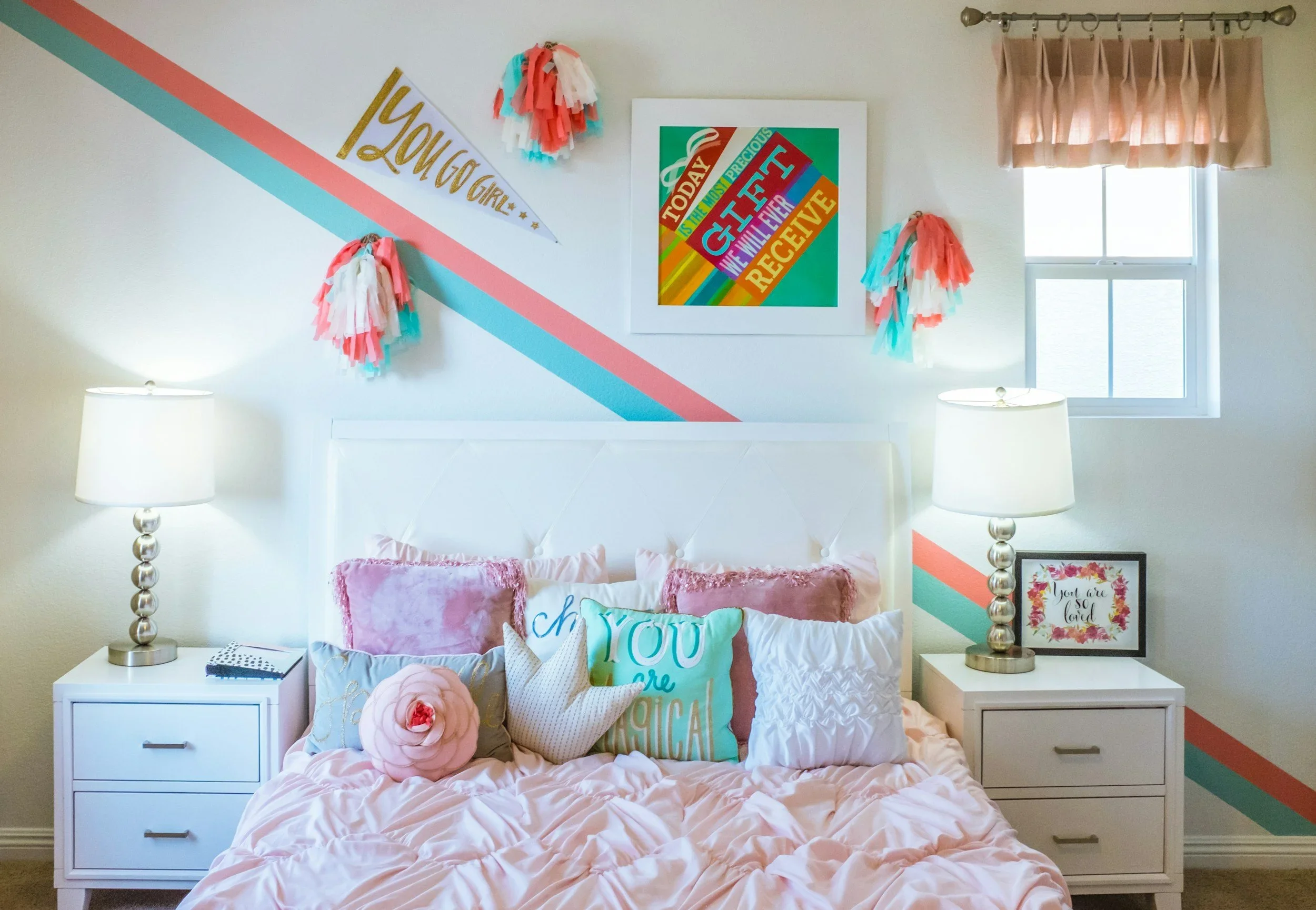 A vibrant, organized girl's bedroom by Makiko Hoff featuring a white tufted headboard, pink bedding, and colorful wall art.