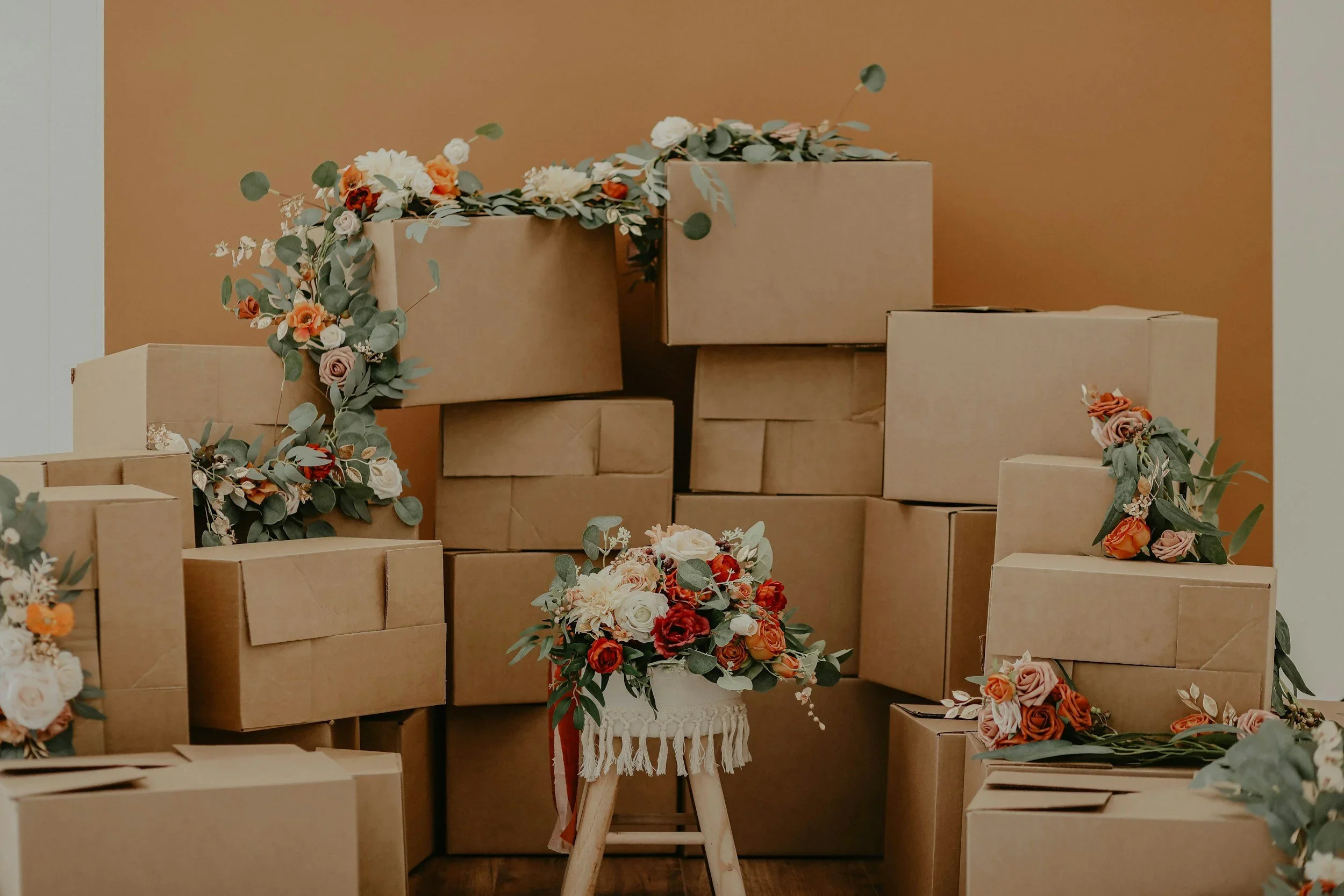 Professional move management by At Your Assistance LLC, featuring stacked brown moving boxes decorated with autumn floral garlands.