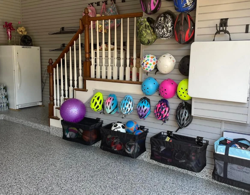 Organized garage in Rochester, MI by Serenity at Home, featuring helmets on a grey slatwall and sports balls in mesh bins.