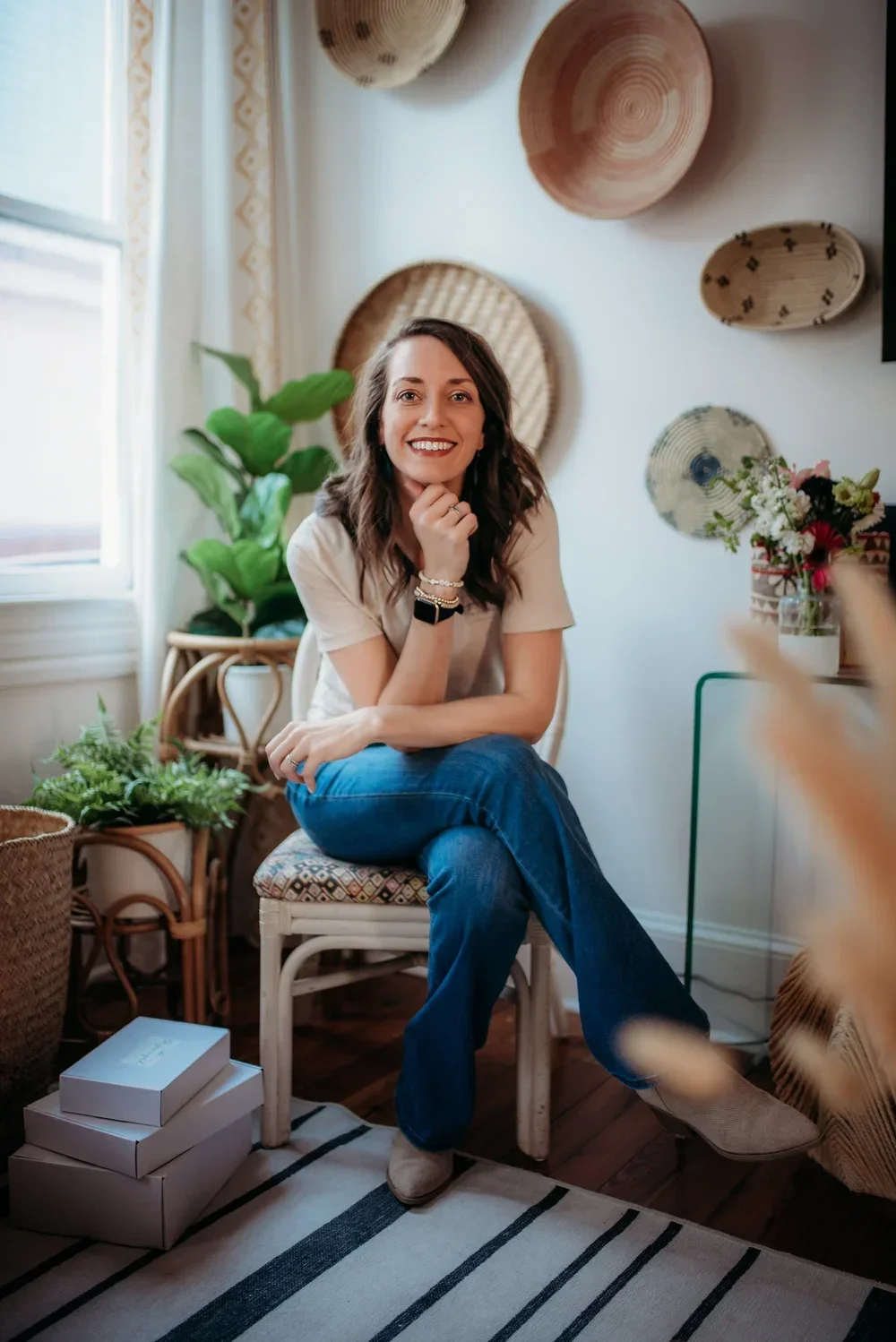 Professional home organizer Hope sitting in a bright, minimalist room with woven wall decor.