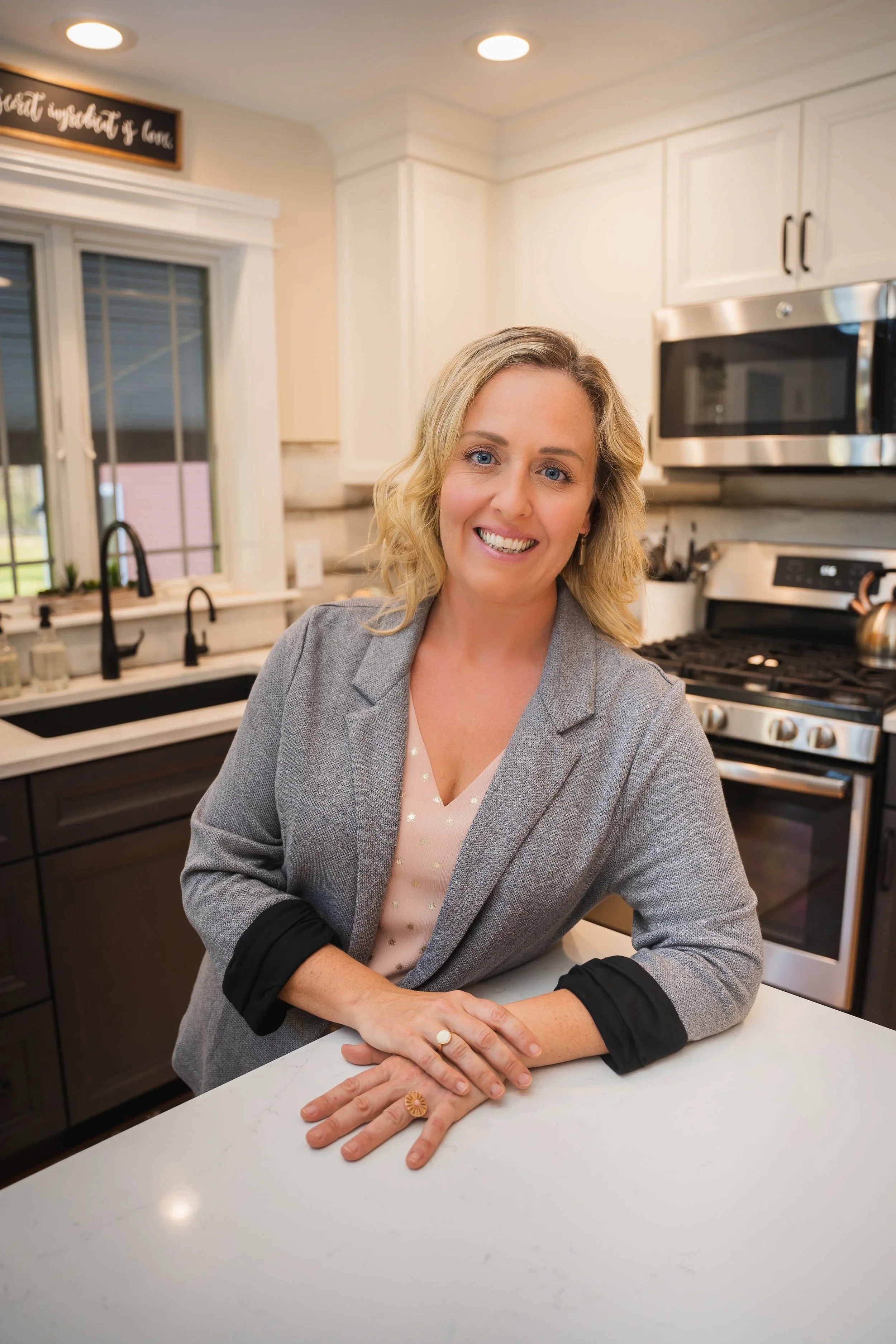 Professional home organizer smiling in a clean, modern kitchen with white countertops.