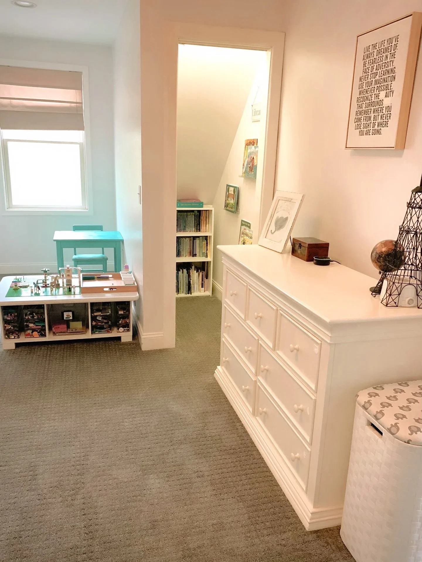 Organized child's playroom by Peaceful Priorities Organizing in Upstate NY, featuring a white dresser and a creative book nook under the stairs.