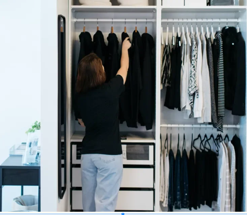 Professional organizer from The Simple Sort arranging a color-coordinated reach-in closet with black and white clothing in Colorado Springs.