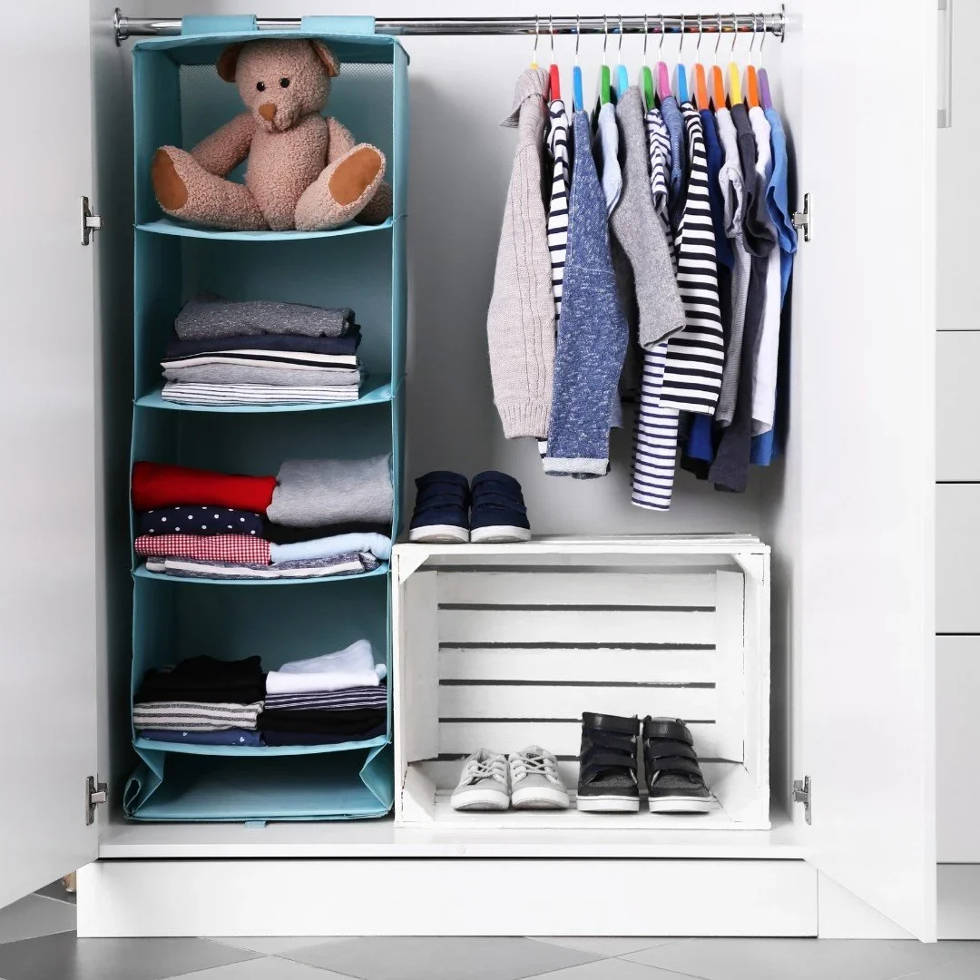 Organized children's closet by A.T. Home Organizing with a blue hanging shelf, colorful hangers, and a shoe crate.
