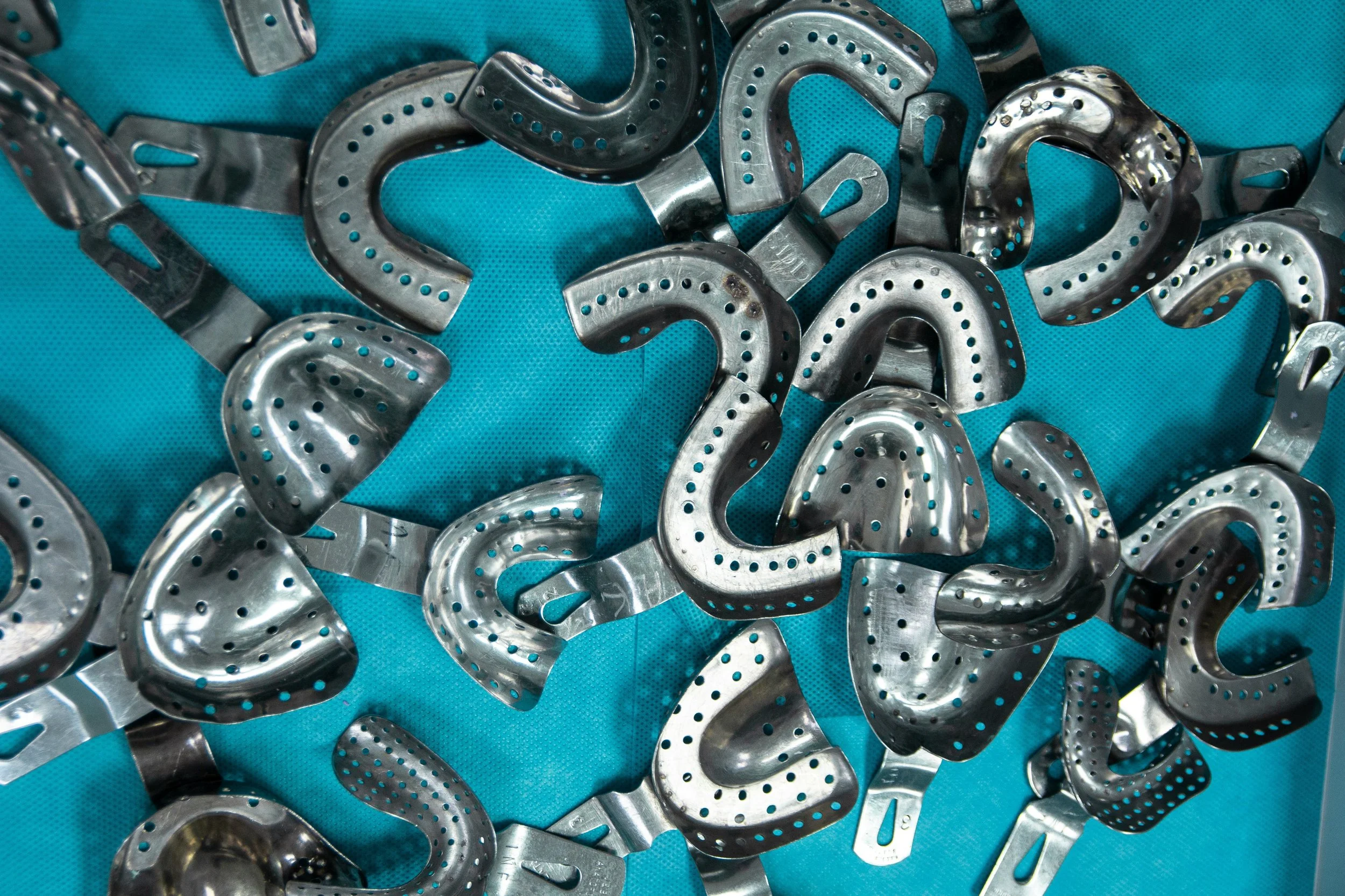 A collection of metal horse head-shaped bottle openers on a blue fabric background.