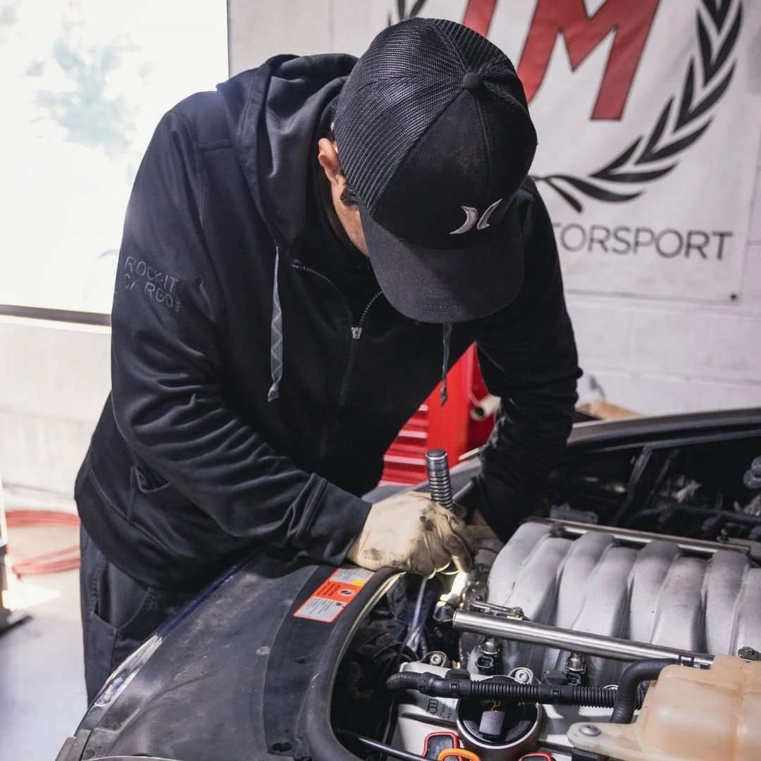 A mechanic in blue gloves and headphones mounting a tire onto a vehicle.