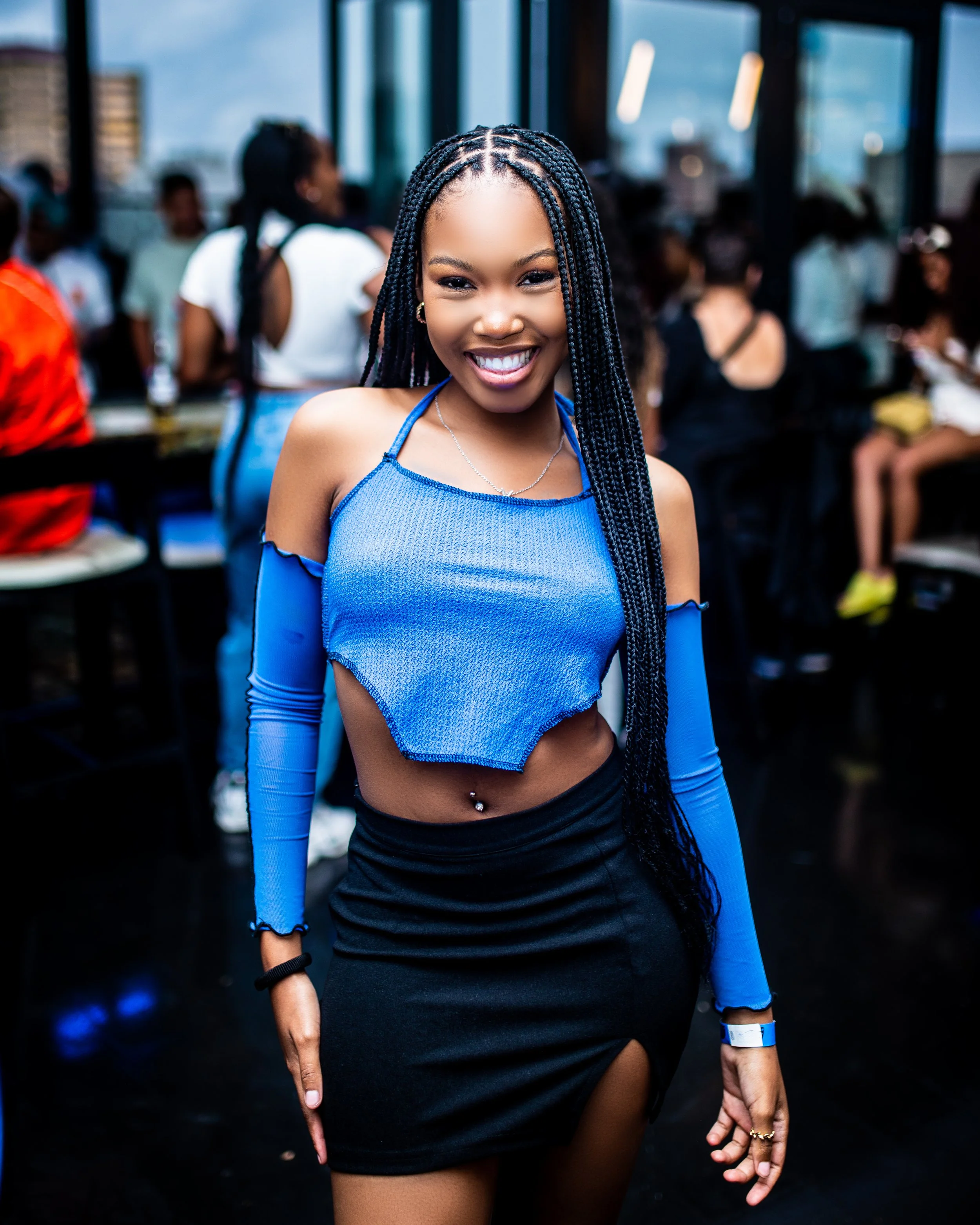 Woman in blue top and black skirt smiling at a party.  Photographed in Johannesburg CBD. 