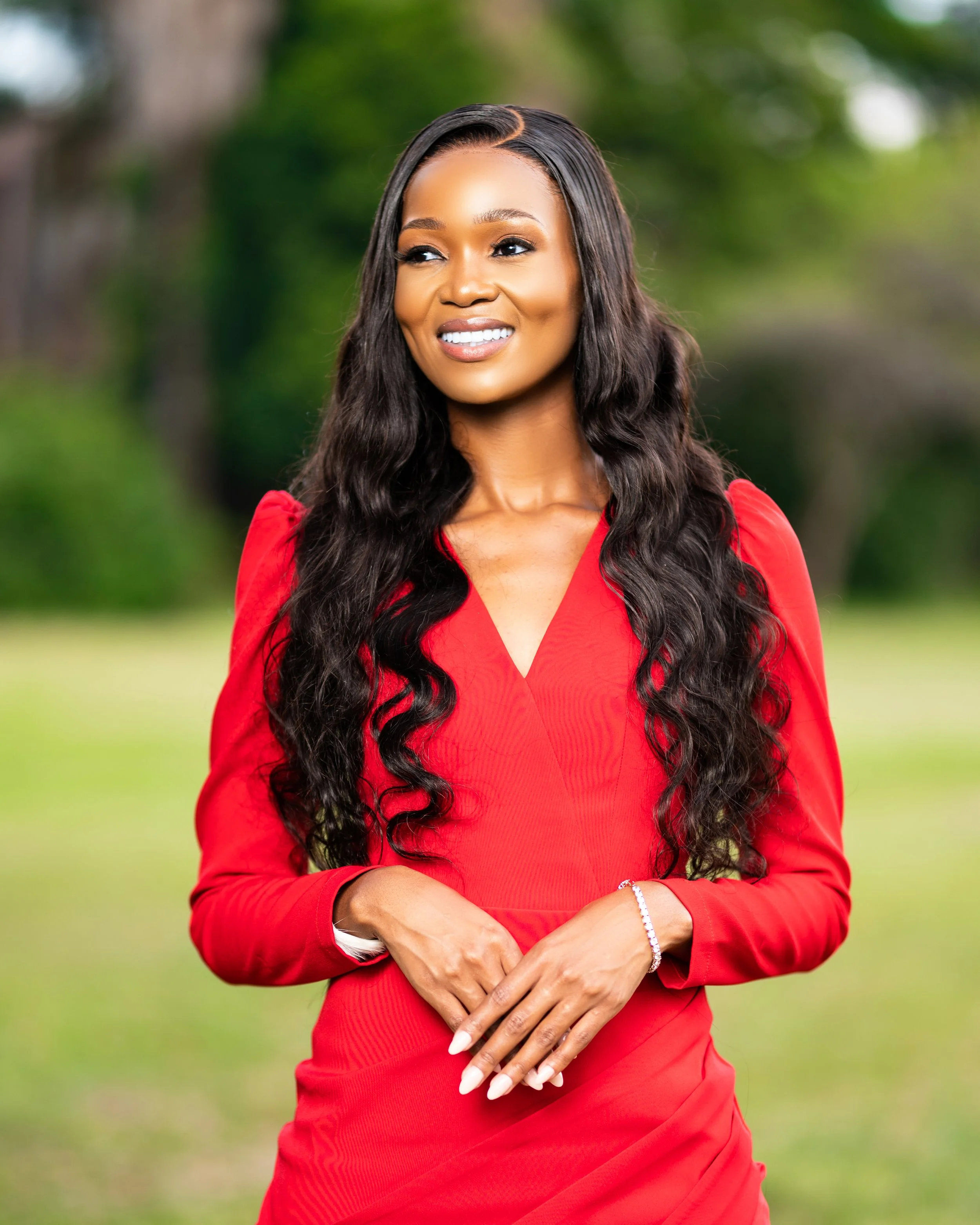 Woman in a red dress smiling outdoors.  Photographed in Pretoria. 