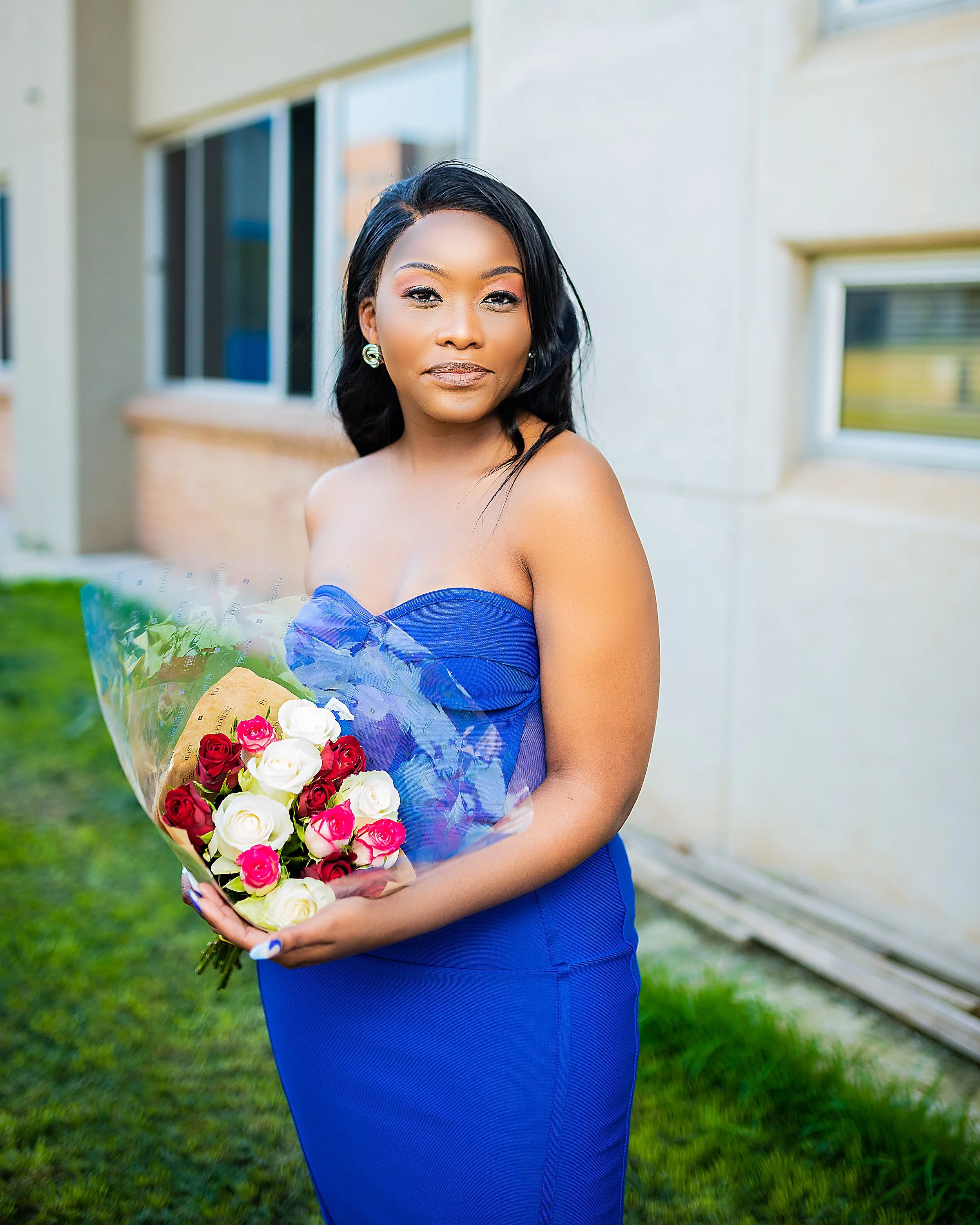 Woman in a blue dress holding a bouquet of roses. Photographed in Soweto, Johannesburg.
