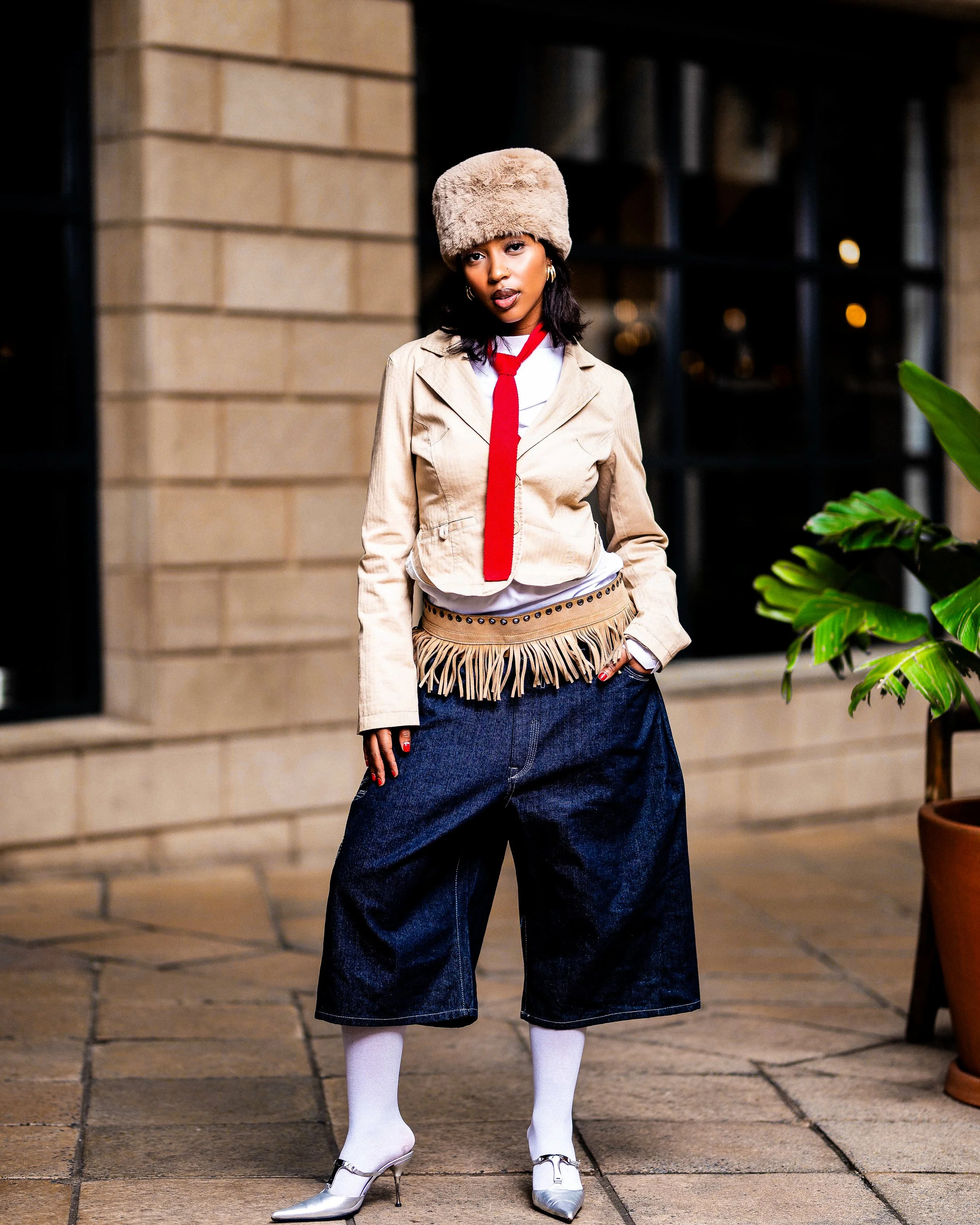 Person in stylish outfit with hat, red tie, and wide denim pants.  Photographed in Melrose Arch, Johannesburg. 