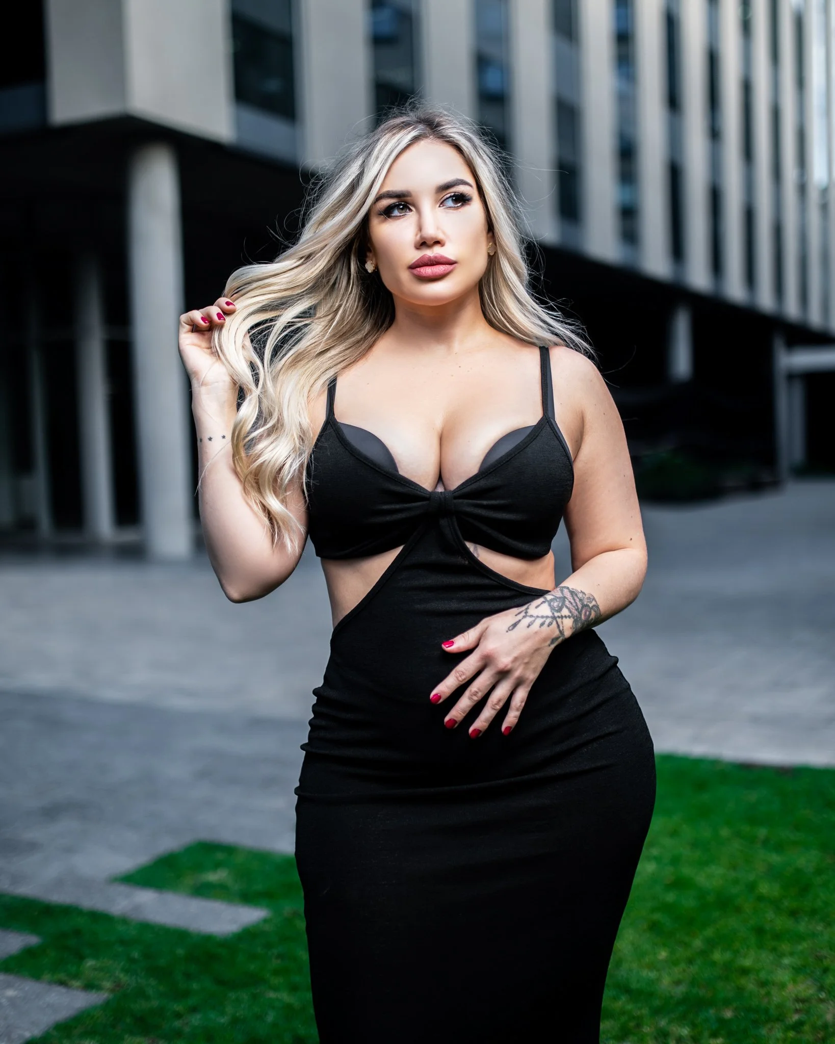 Woman in black dress with blond hair standing outdoors near modern building.  Photographed in Rosebank, Johannesburg. 