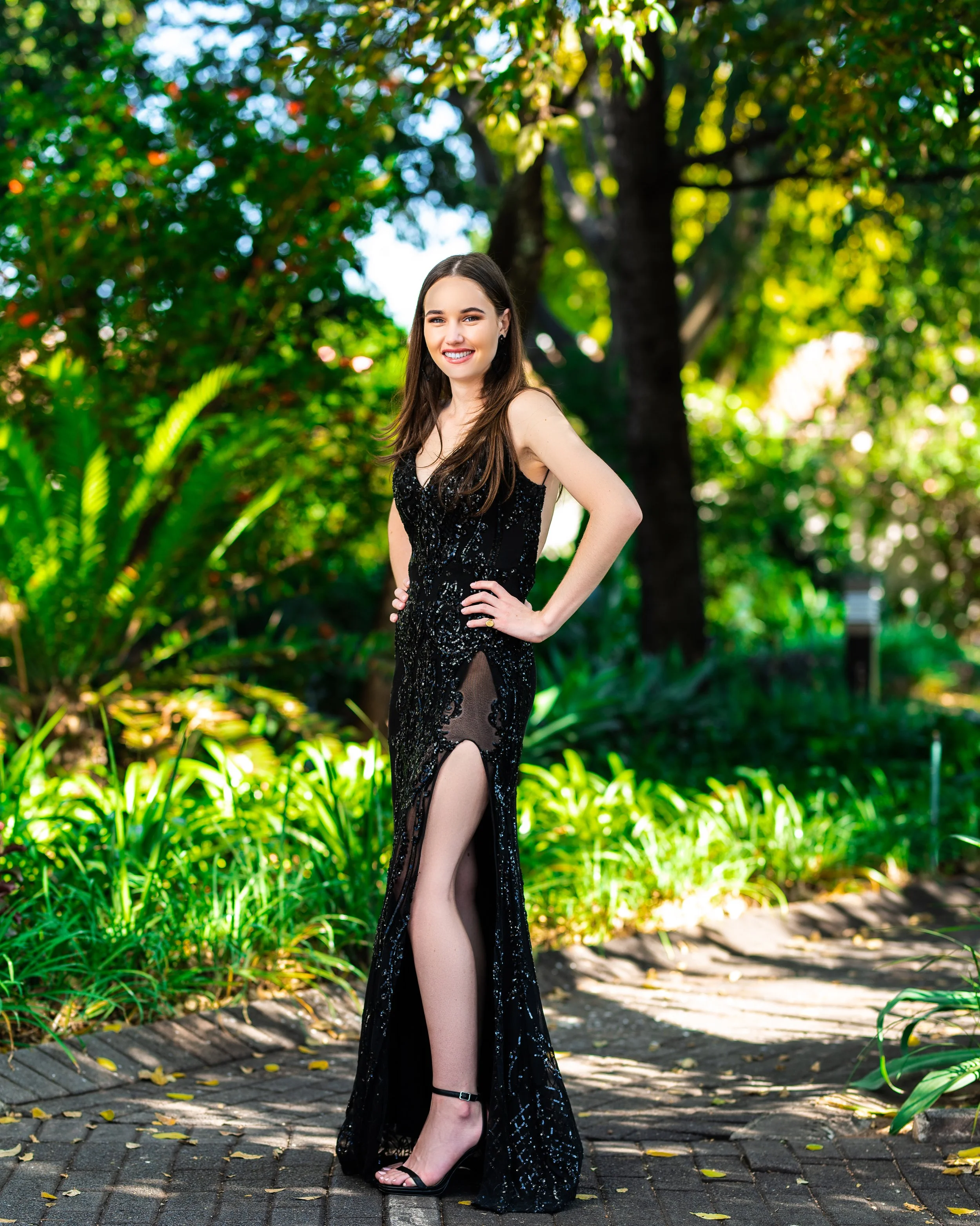 Woman in a black evening gown standing on a garden pathway. Photographed in Johannesburg, South Africa.