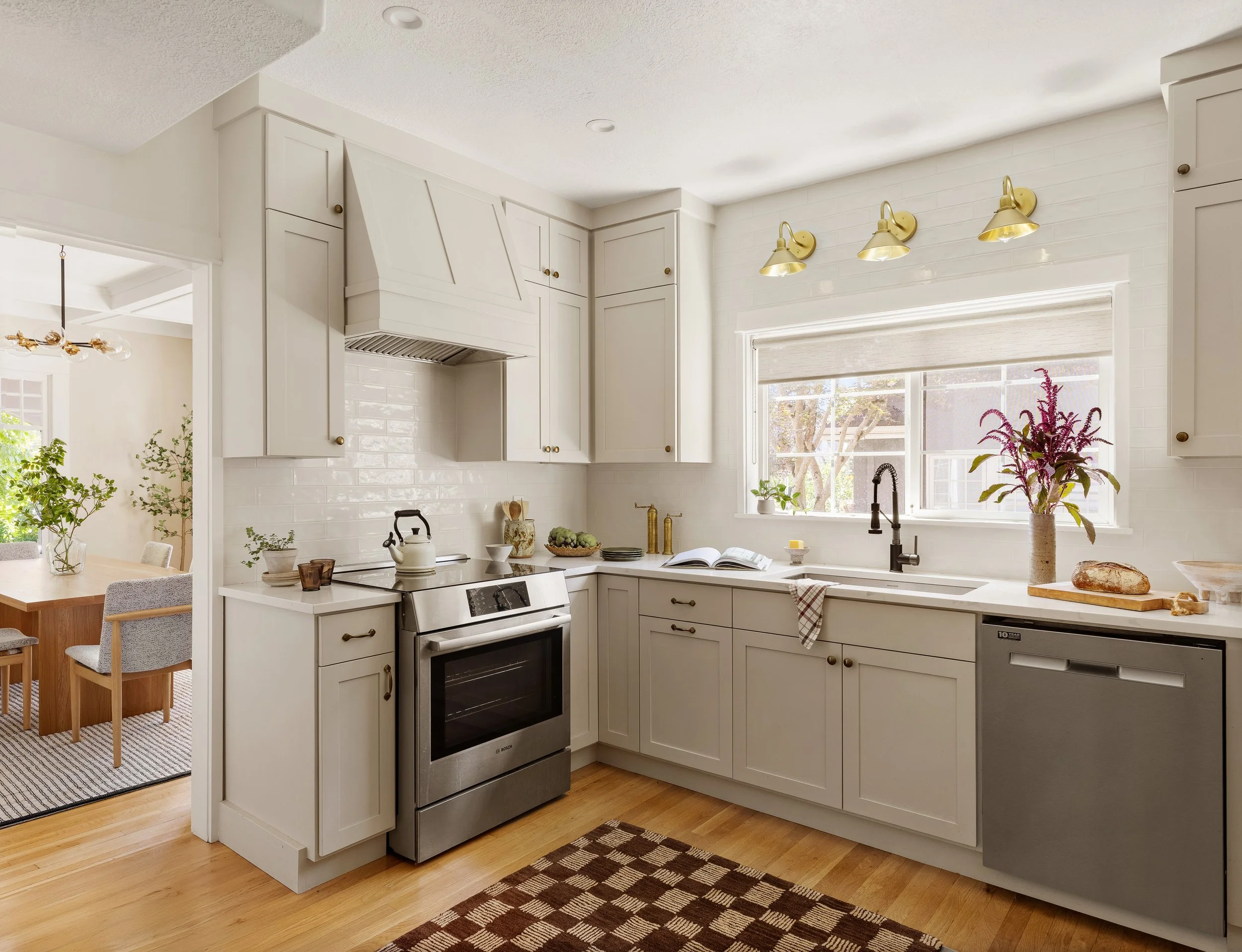 Portland OR kitchen renovation by interior designer Anna Reinhard Interiors with creamy white cabinets, stainless steel appliances, white oak floors, brass fixtures and hardware.