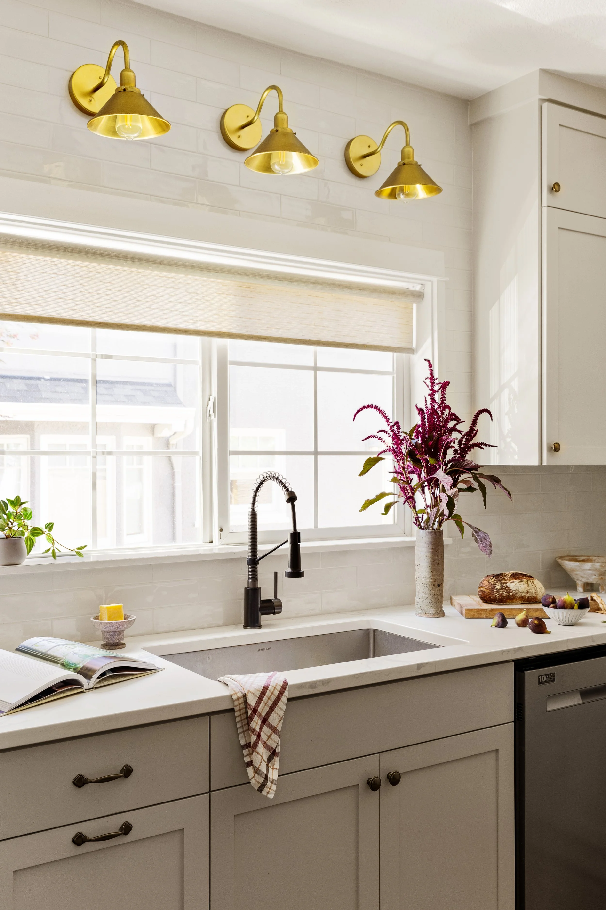 Portland OR kitchen renovation by interior designer Anna Reinhard Interiors with creamy white cabinets, stainless steel appliances, white oak floors, brass fixtures and hardware. Bright and warm interior design.