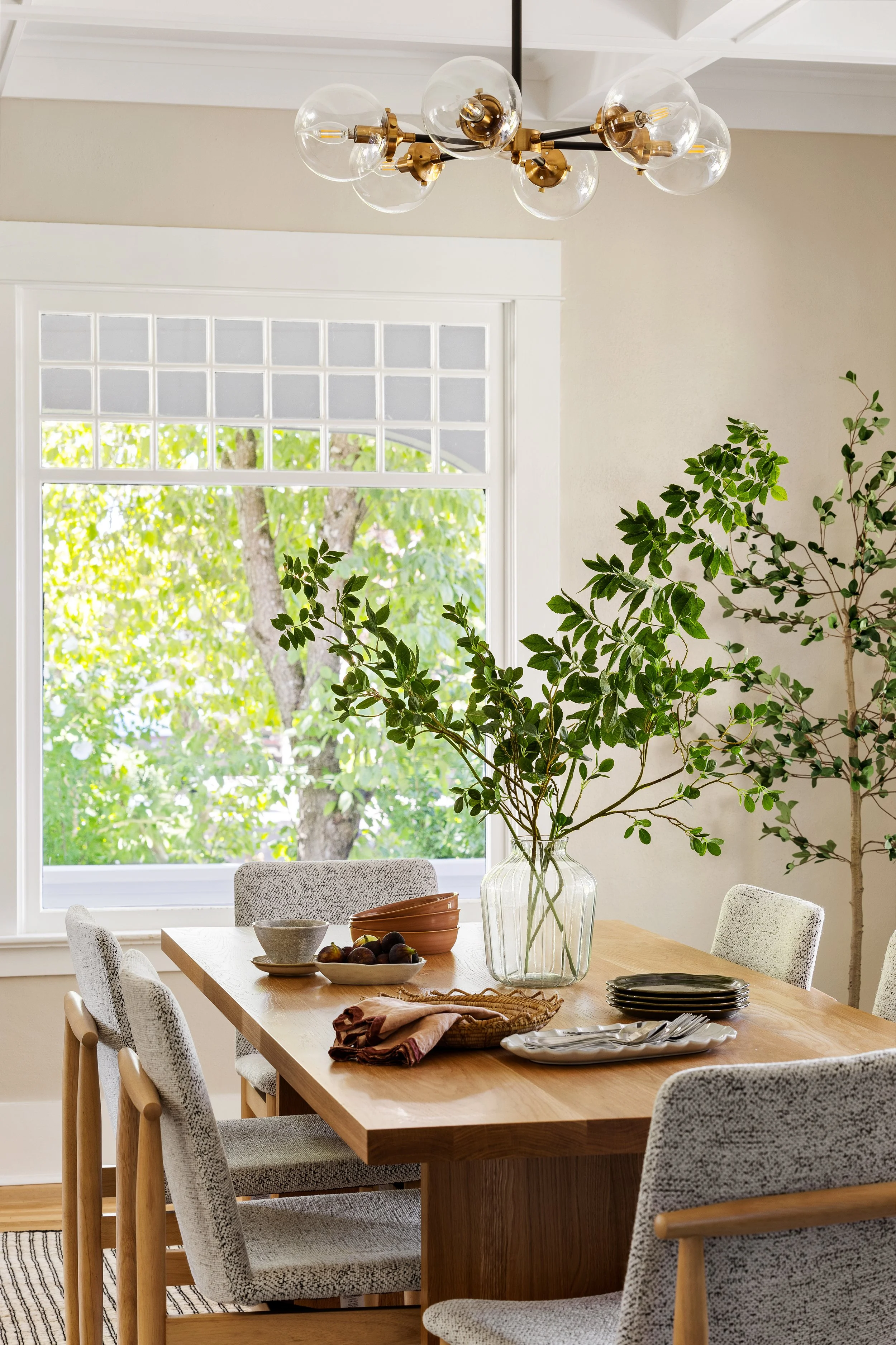 Dining room renovation by Portland OR interior designer. Bright walls, warm white oak dining table and chairs, brass and bronzed chandelier, and vintage Niels Moller chair. Earthy, inviting and textural interior design.
