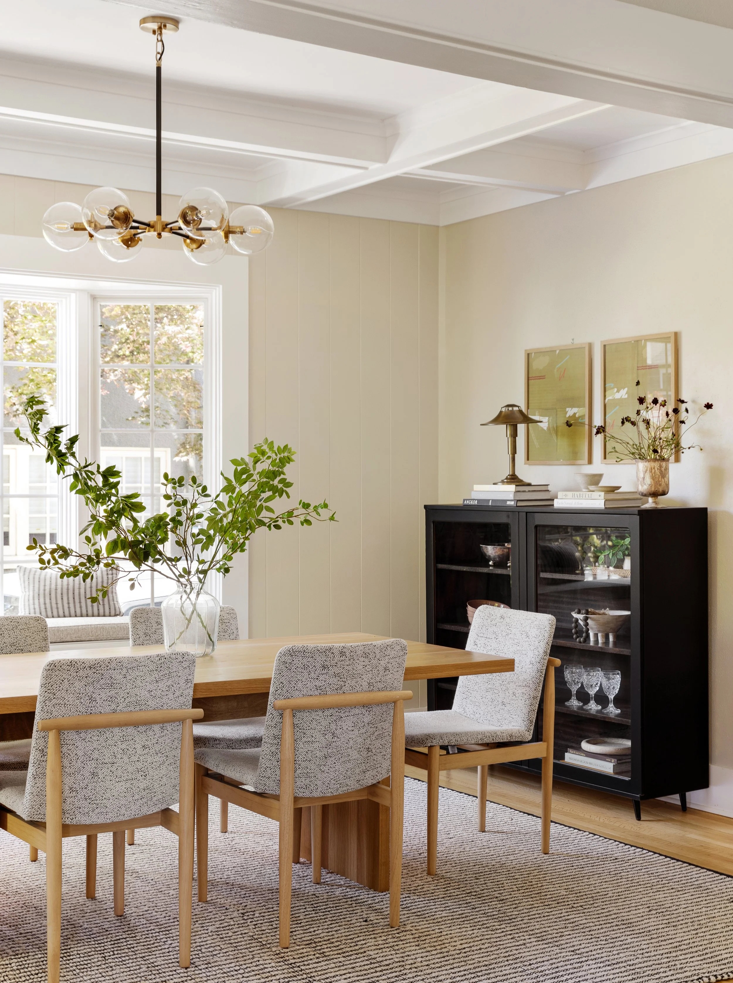 Dining room renovation by Portland OR interior designer Anna Reinhard Interiors. Upholstered dining chairs, vintage black cabinet, white oak dining table, textural rug and brass chandelier.