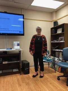Woman standing in a classroom with a presentation screen and bookshelves