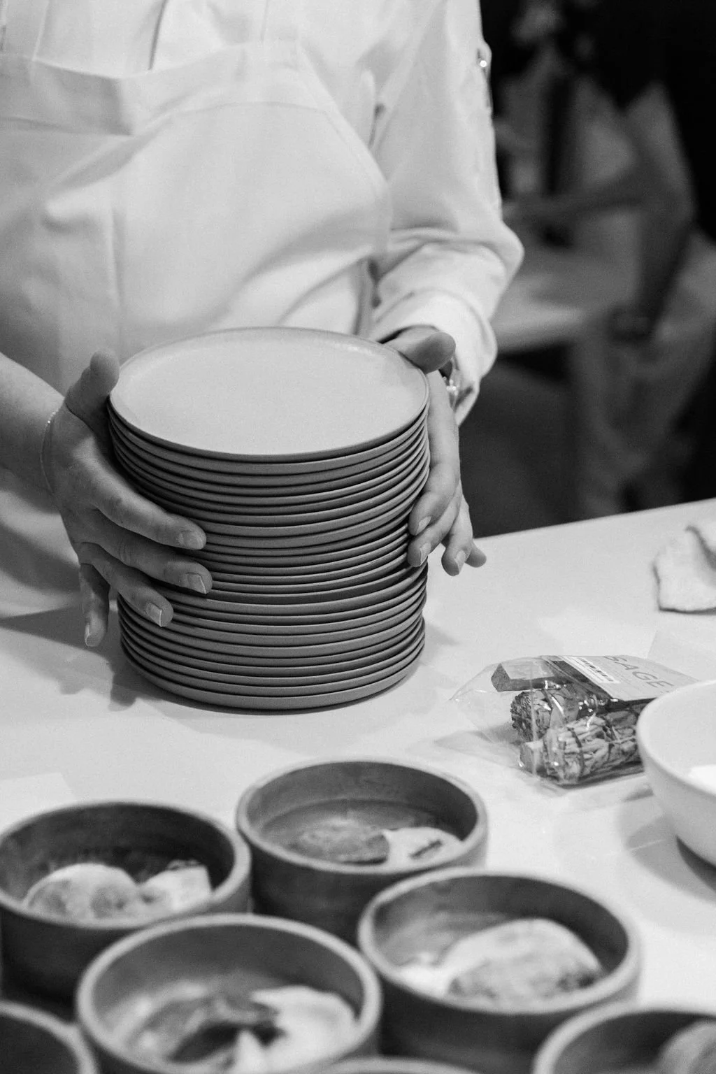 A person in a white shirt is stacking empty plates on a table at what appears to be a gathering or event.