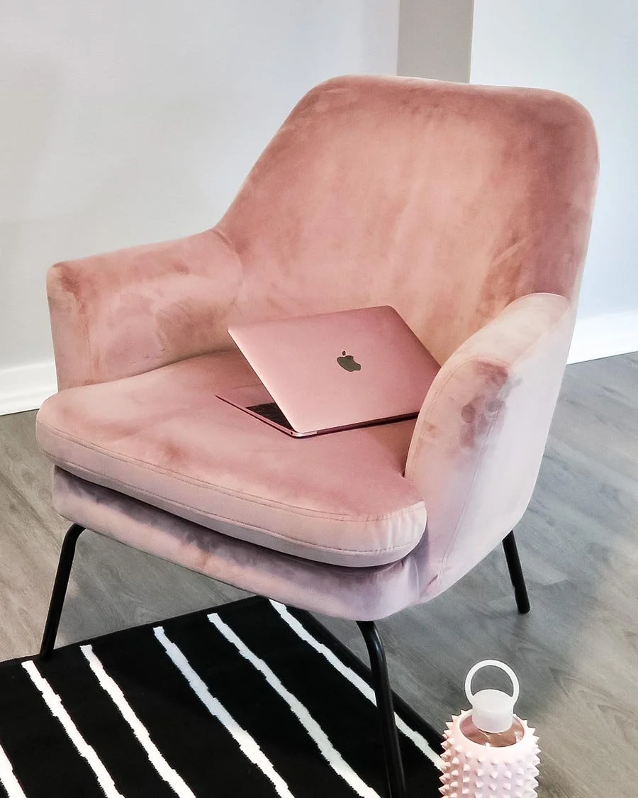 Photo of a pink Macbook laptop on a pink office chair