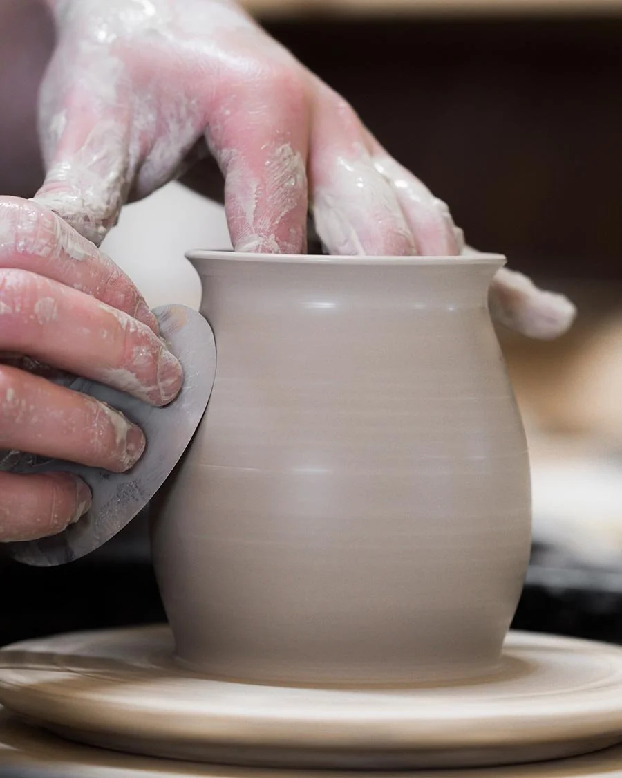 Photo of someone maying a clay vessel on a ceramic wheel