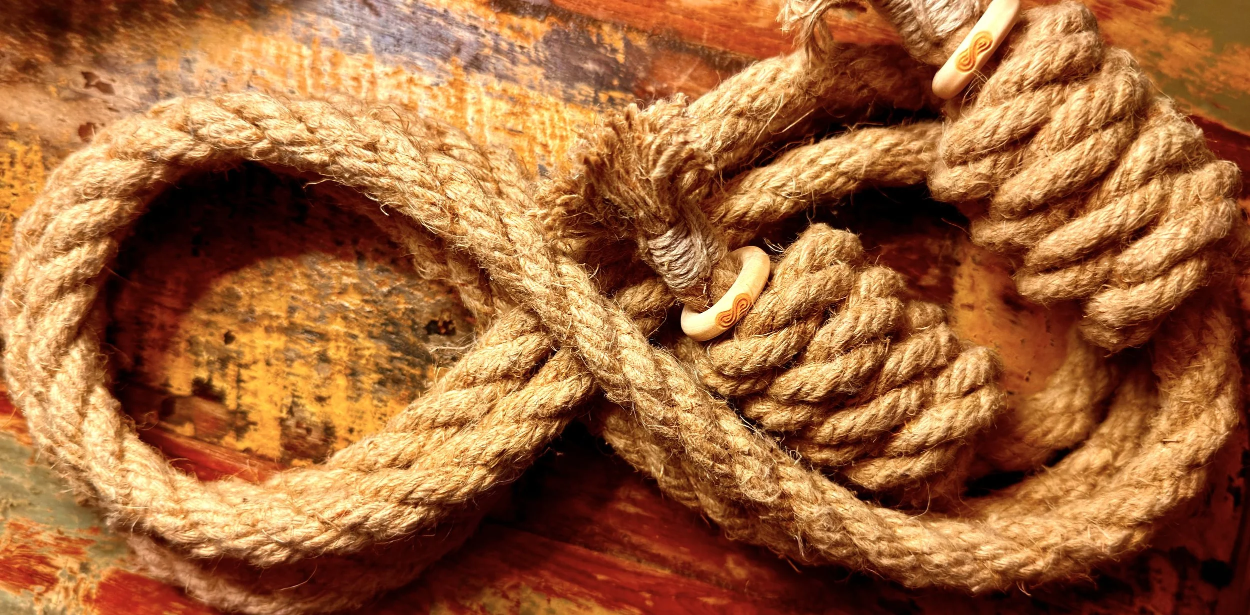Hemp rope laid in an infinity loop shape. , resting on a colorful, distressed wooden surface.