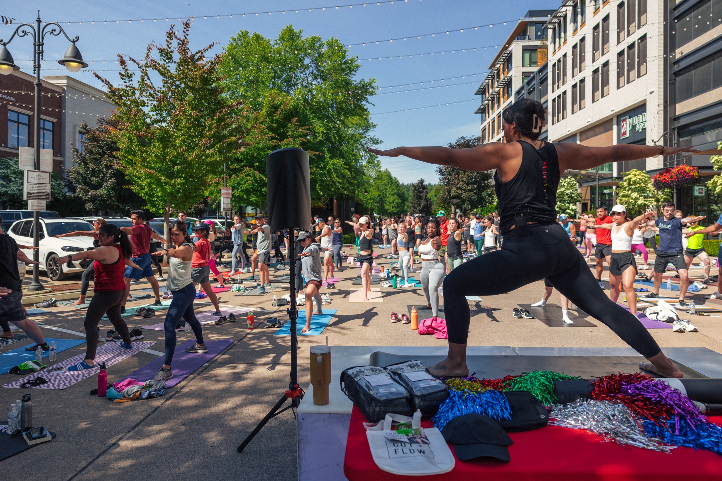 Yoga class at an outdoor event, led by a BIPOC instructor with 30+ participants on mats