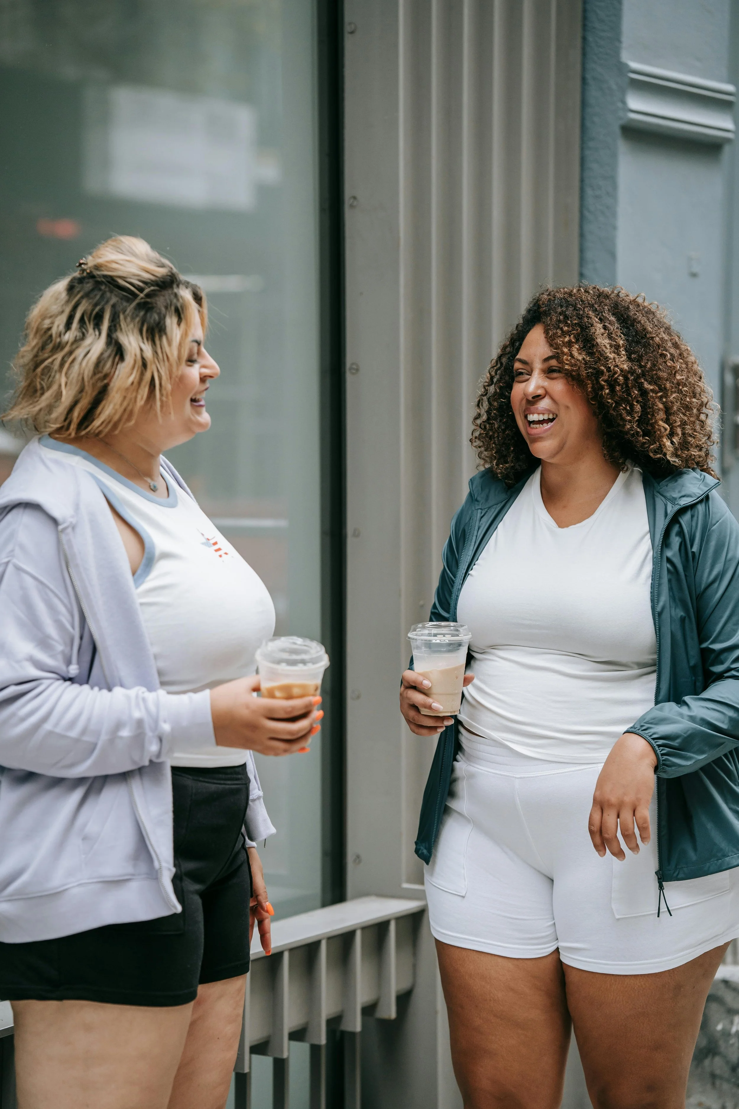 Two diverse woman laughing and drinking coffee