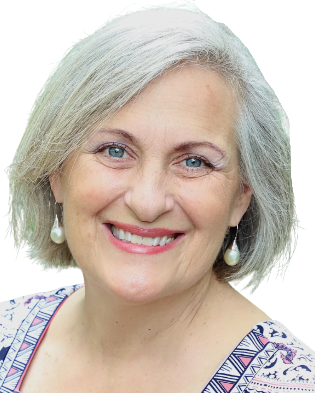 Close-up photo of a smiling middle-aged woman with gray hair, blue eyes, pearl earrings, and wearing a patterned top.
