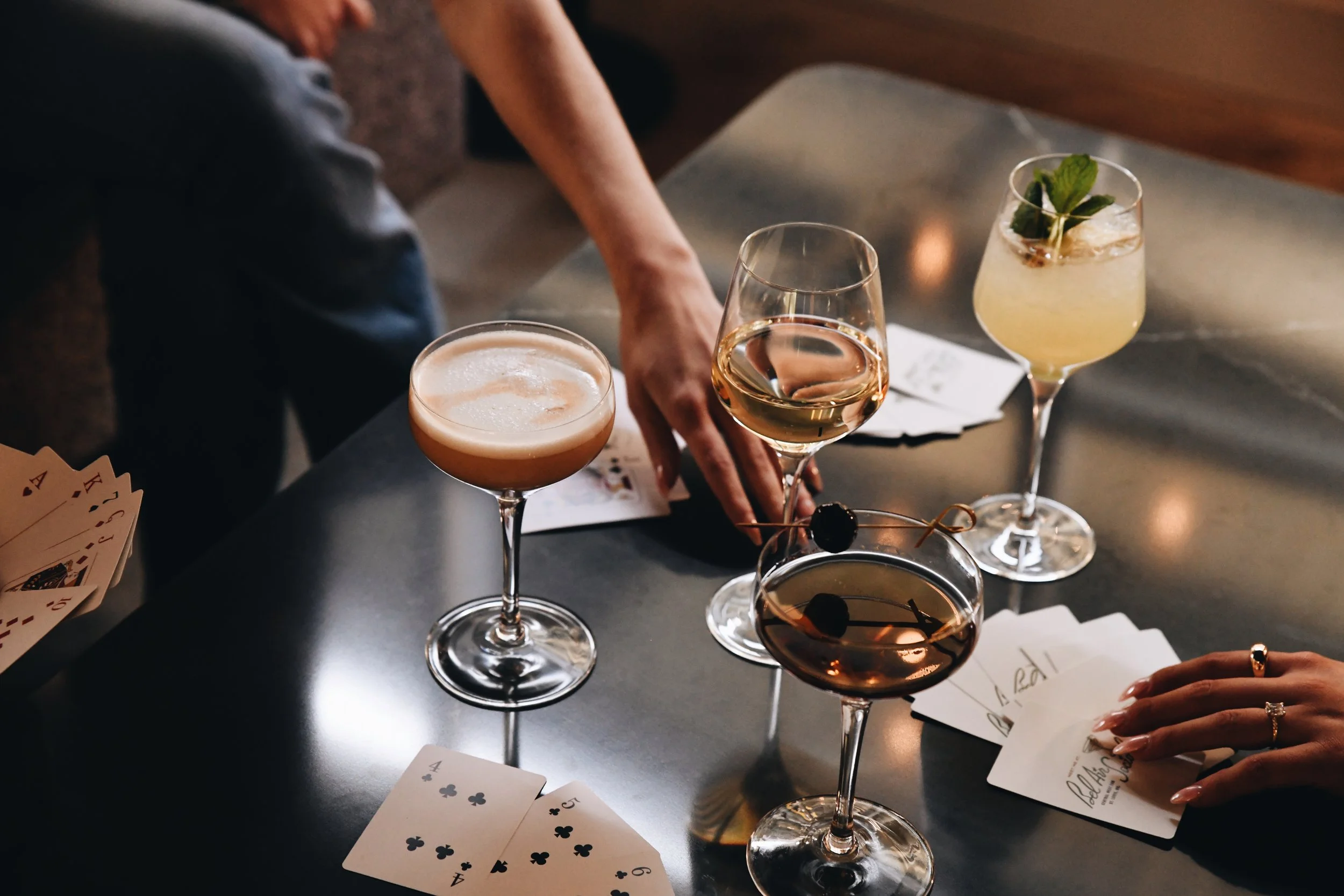Close-up of two women holding cocktails and socializing in a dimly lit setting, possibly a bar or nightclub.