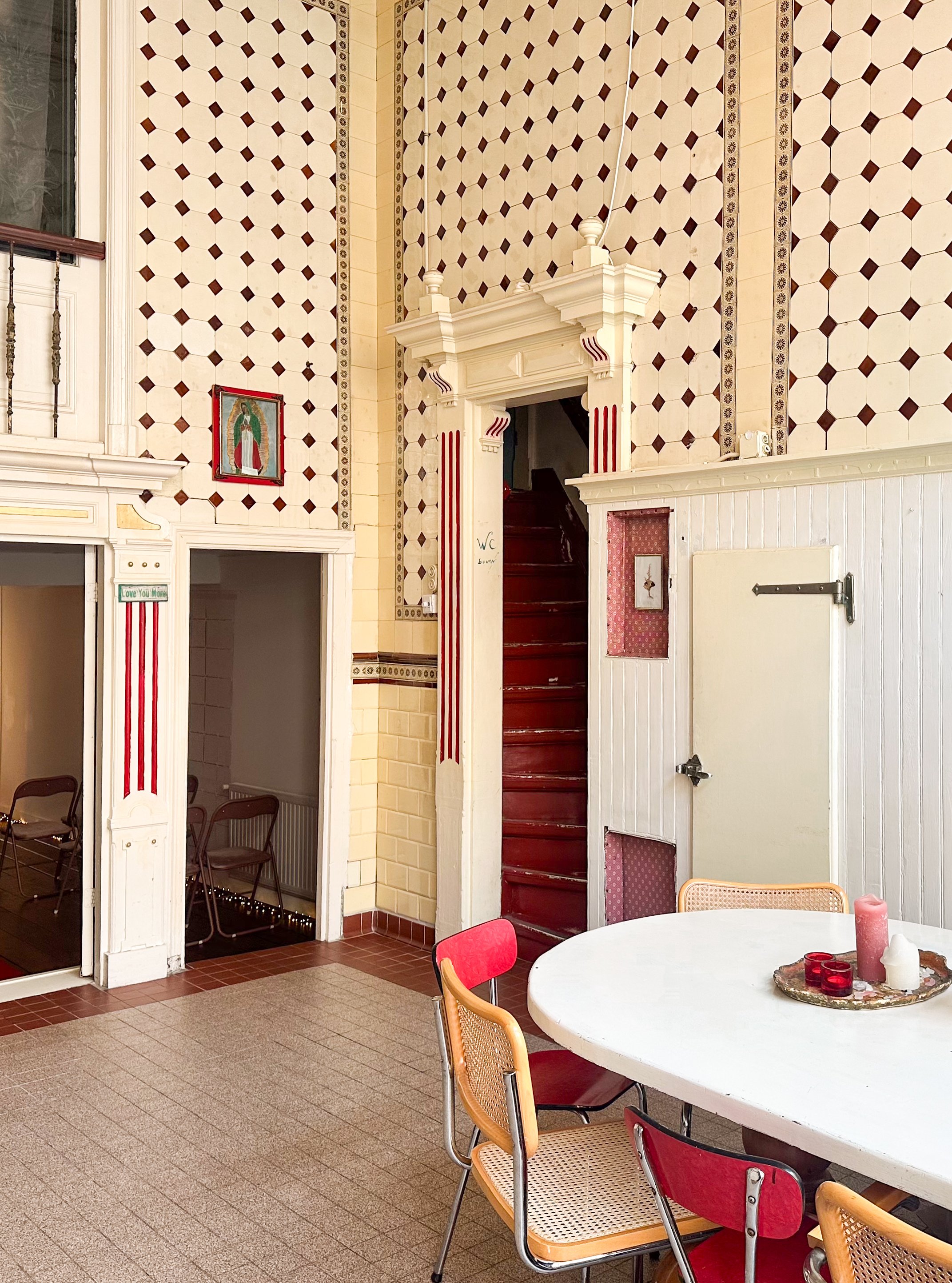 Interieur van een kamer met een ronde tafel en stoelen, decoratieve muren en een trap in een vintage stijl.