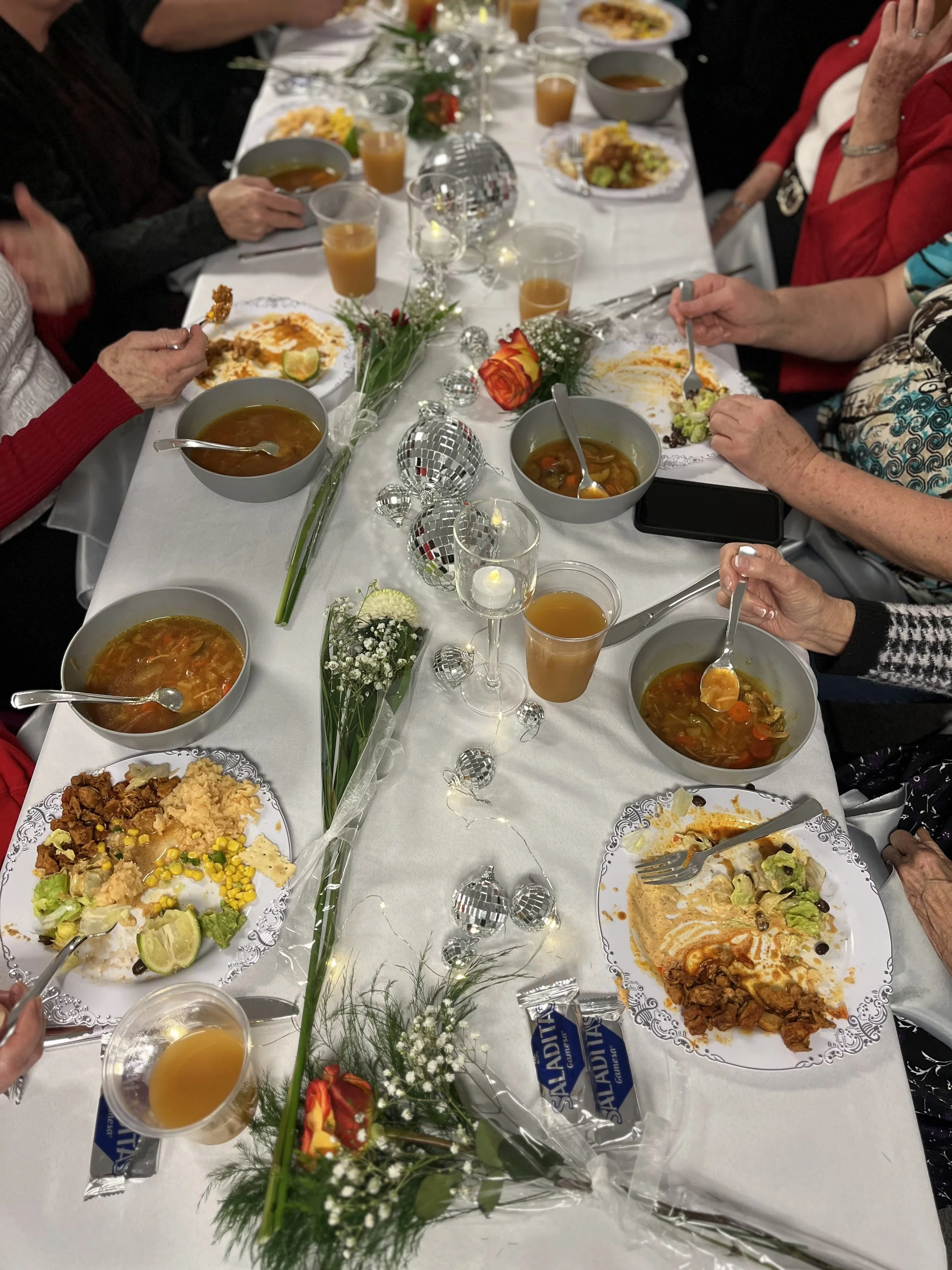 floral centerpiece featuring pink and yellow flowers on a dining table with blue plates and gold utensils