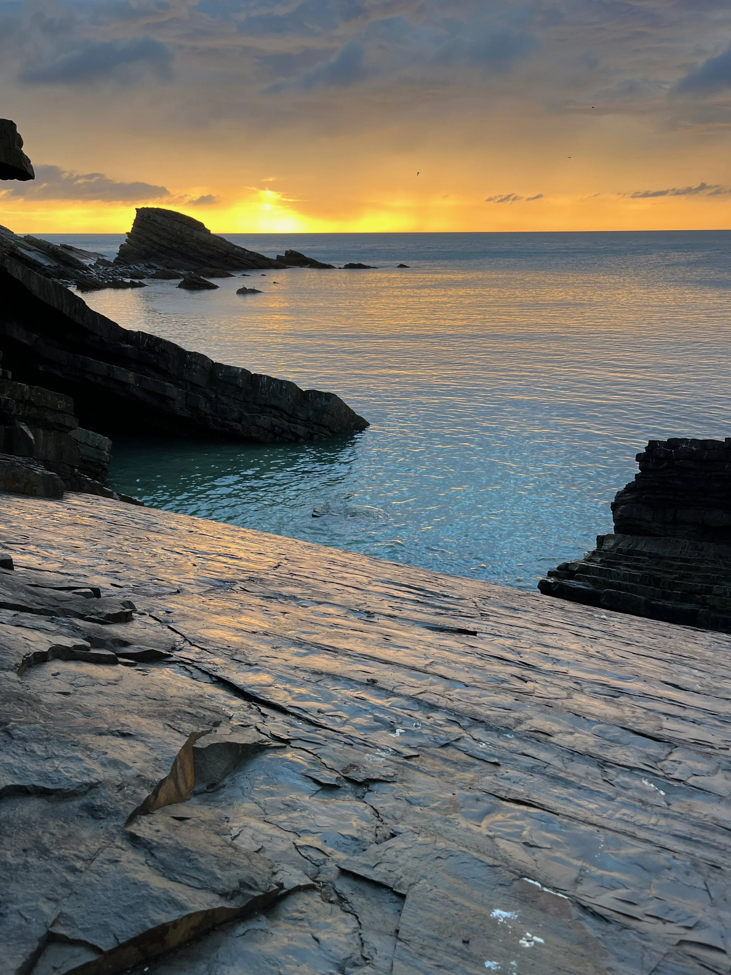 Rocky shoreline with sunset over the ocean