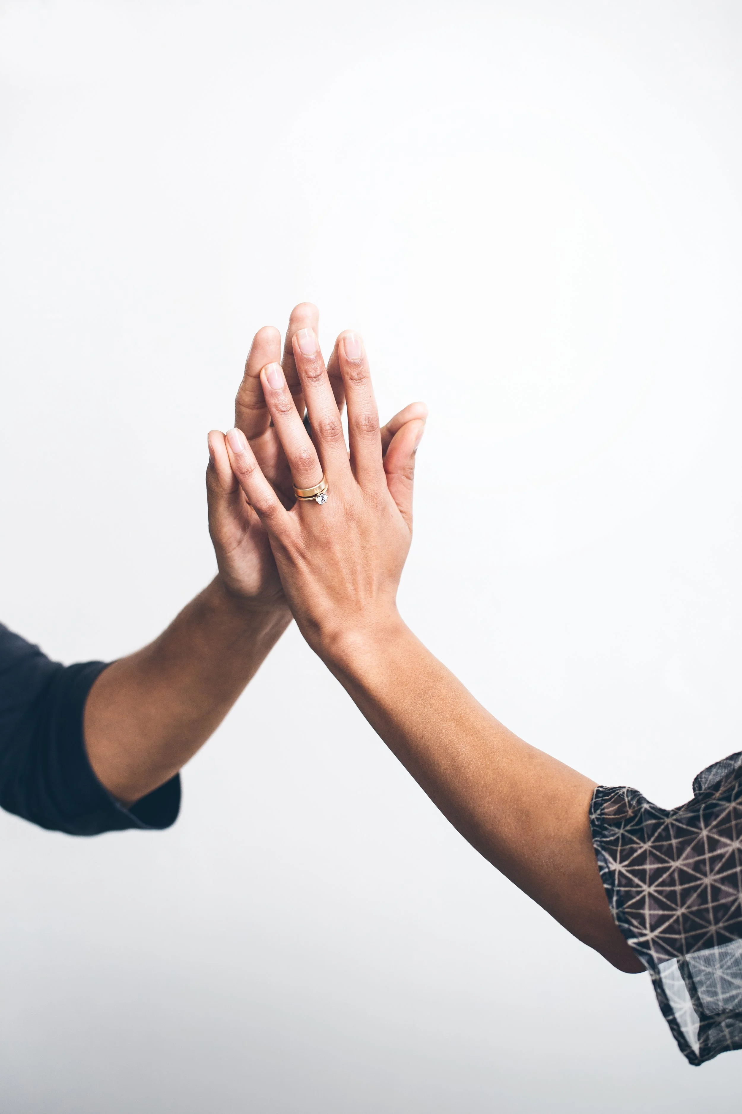 Two hands touching in a high five, with a white background.