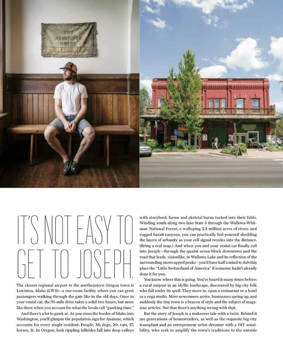 Photo of a man sitting on a wooden bench inside a restaurant, looking out a window to his left. He is wearing a white t-shirt, shorts, a baseball cap, and sandals. The interior has wood paneling and a decorative wall hanging. Next to the photo, there