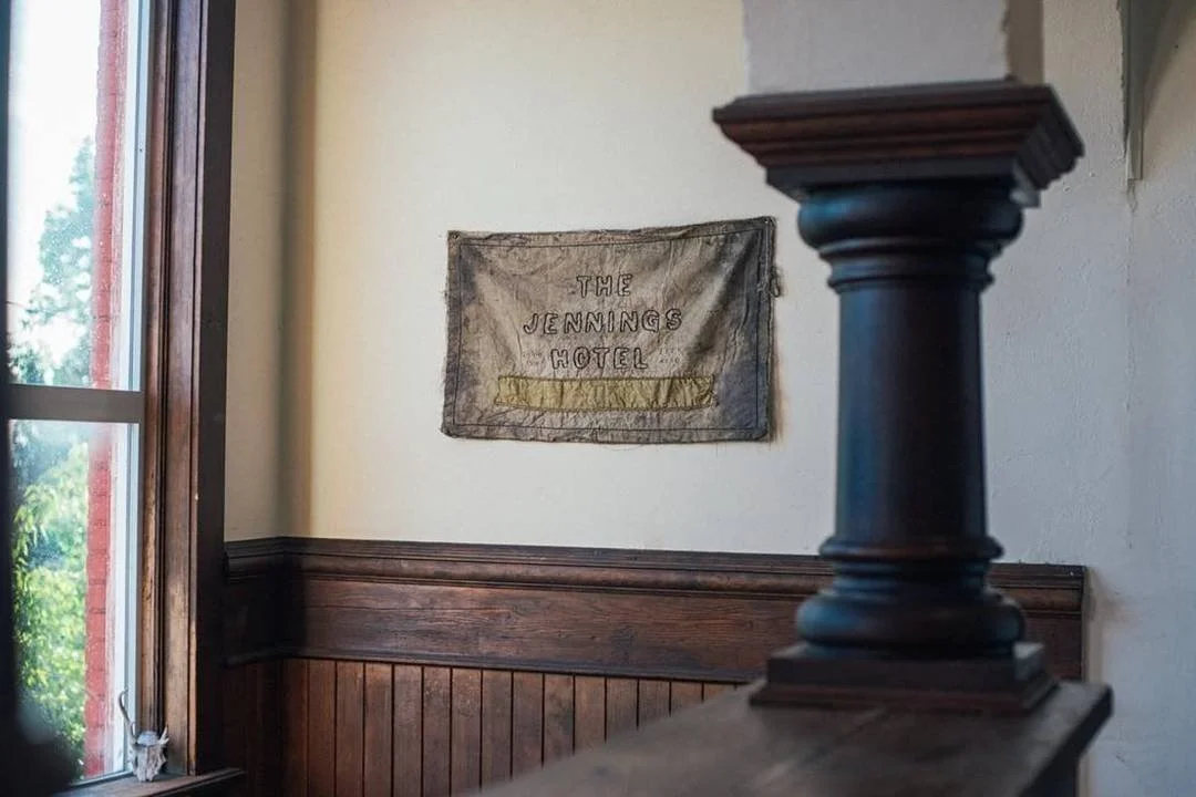 Interior of the Jennings Hotel with a fabric sign on the wall and a wooden railing with a decorative post.