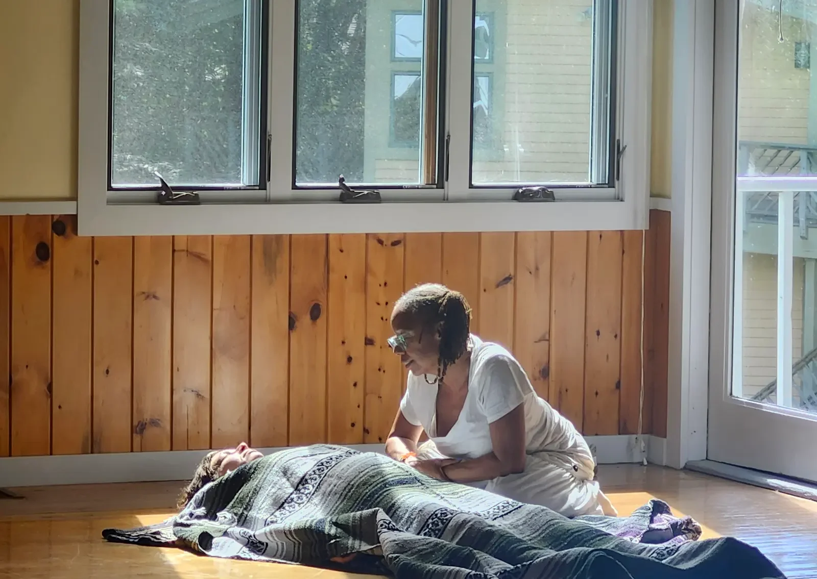 woman relaxing on floor while another woman looks at her with love