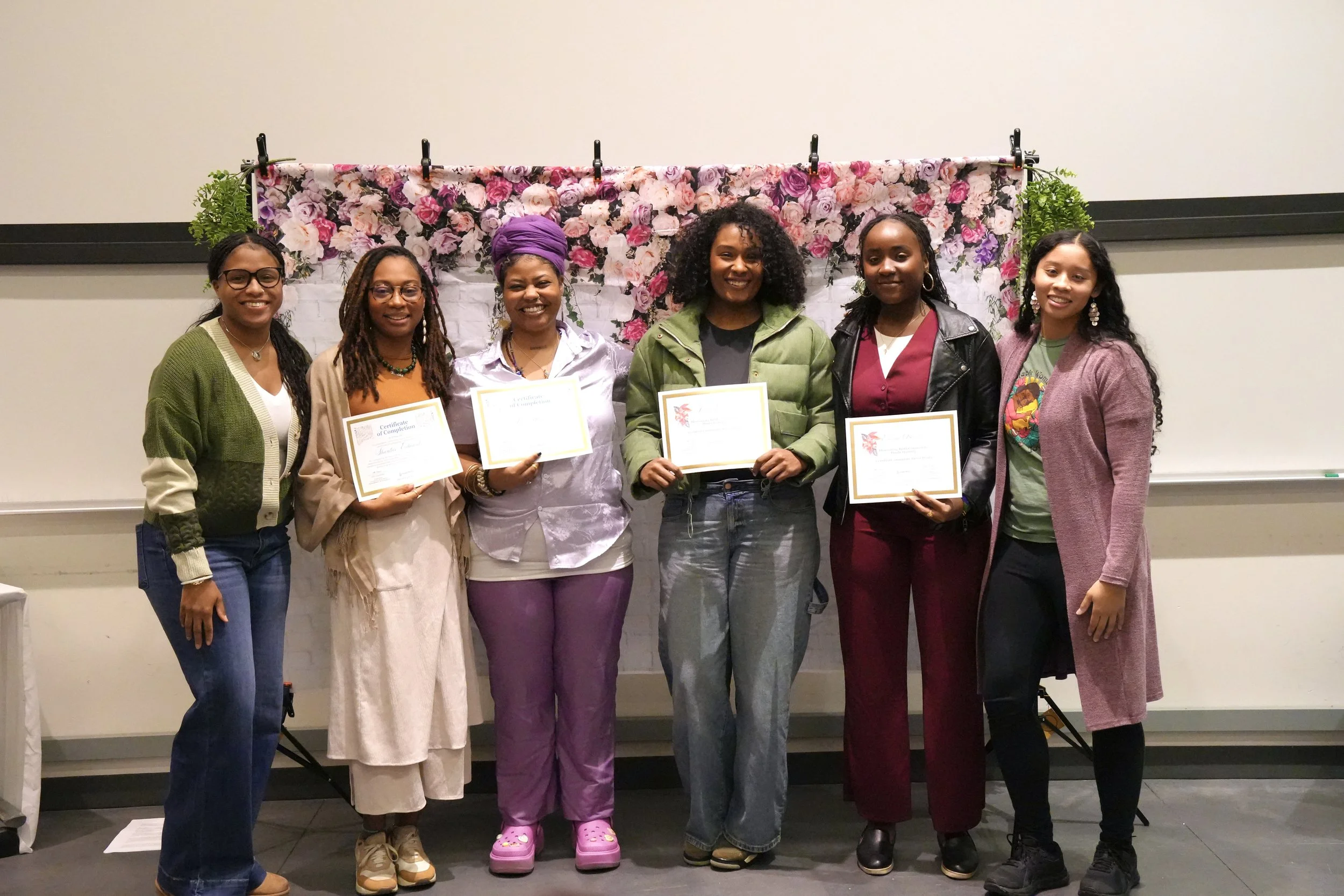 six BIPOC women pose with diplomas