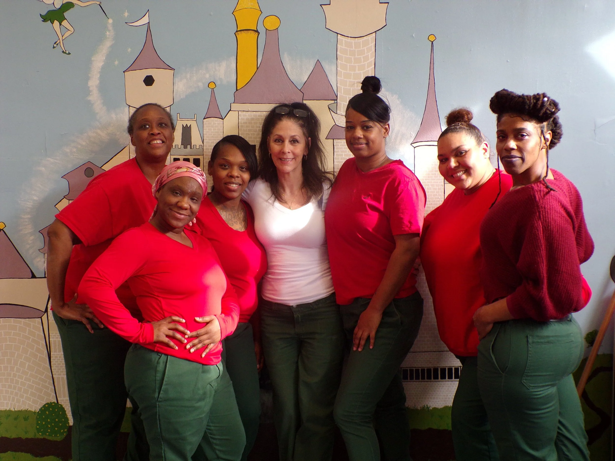 7 women standing together smiling in the nursery of the correctional facility